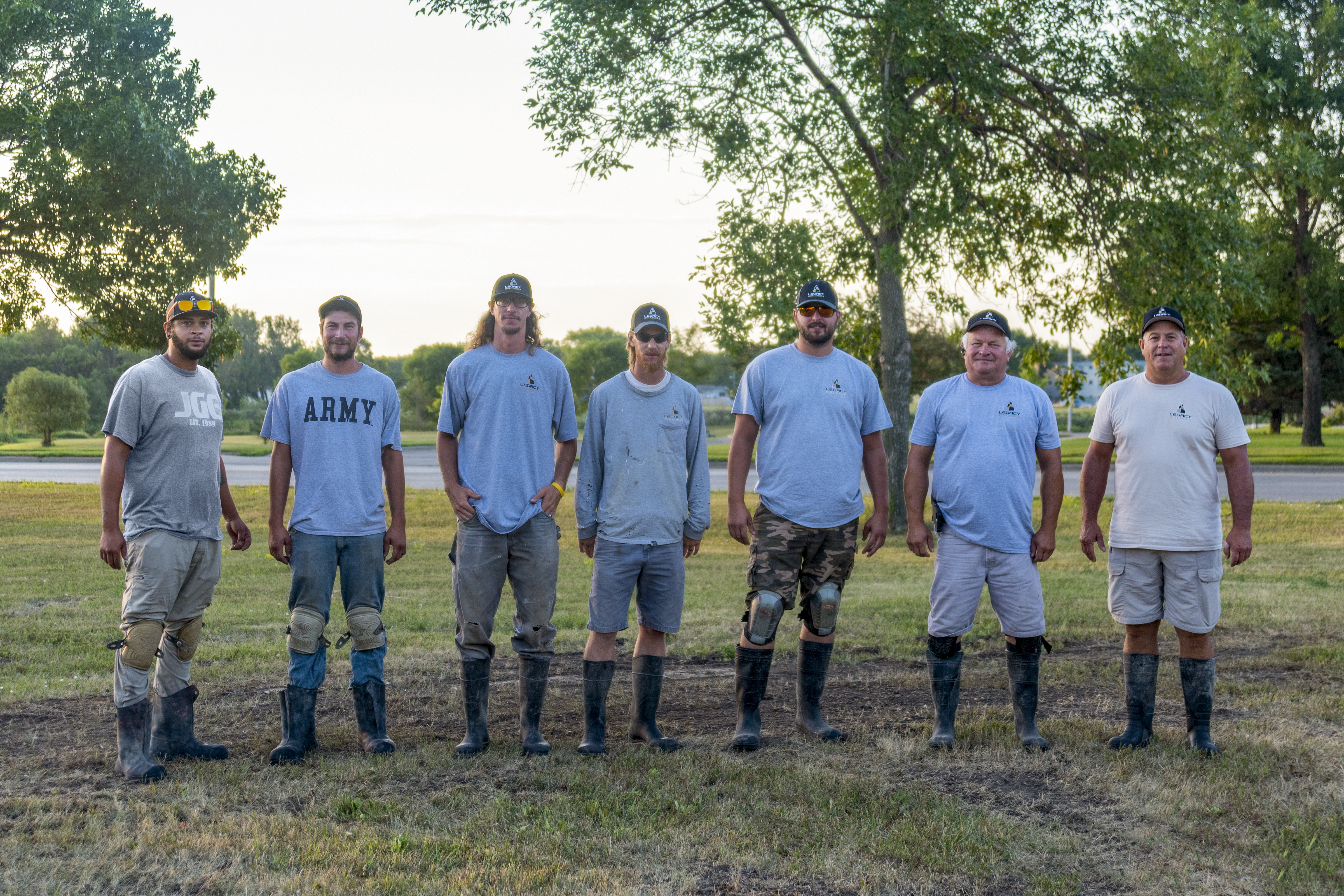 Seven workers stand at the ready in their mud boots ahead of pouring concrete for a new basketball court