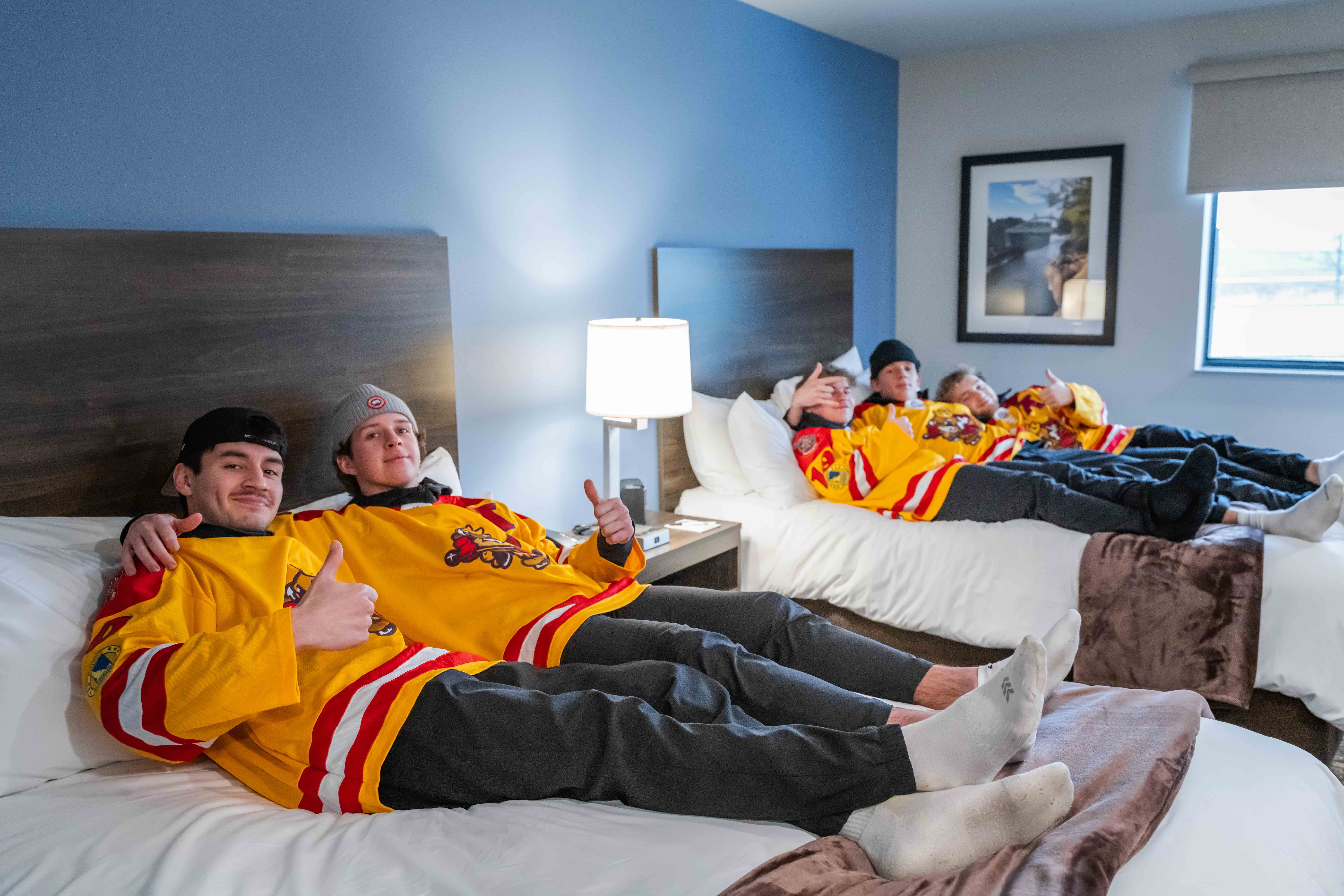 A group of guys laying down on My Place Hotel beds