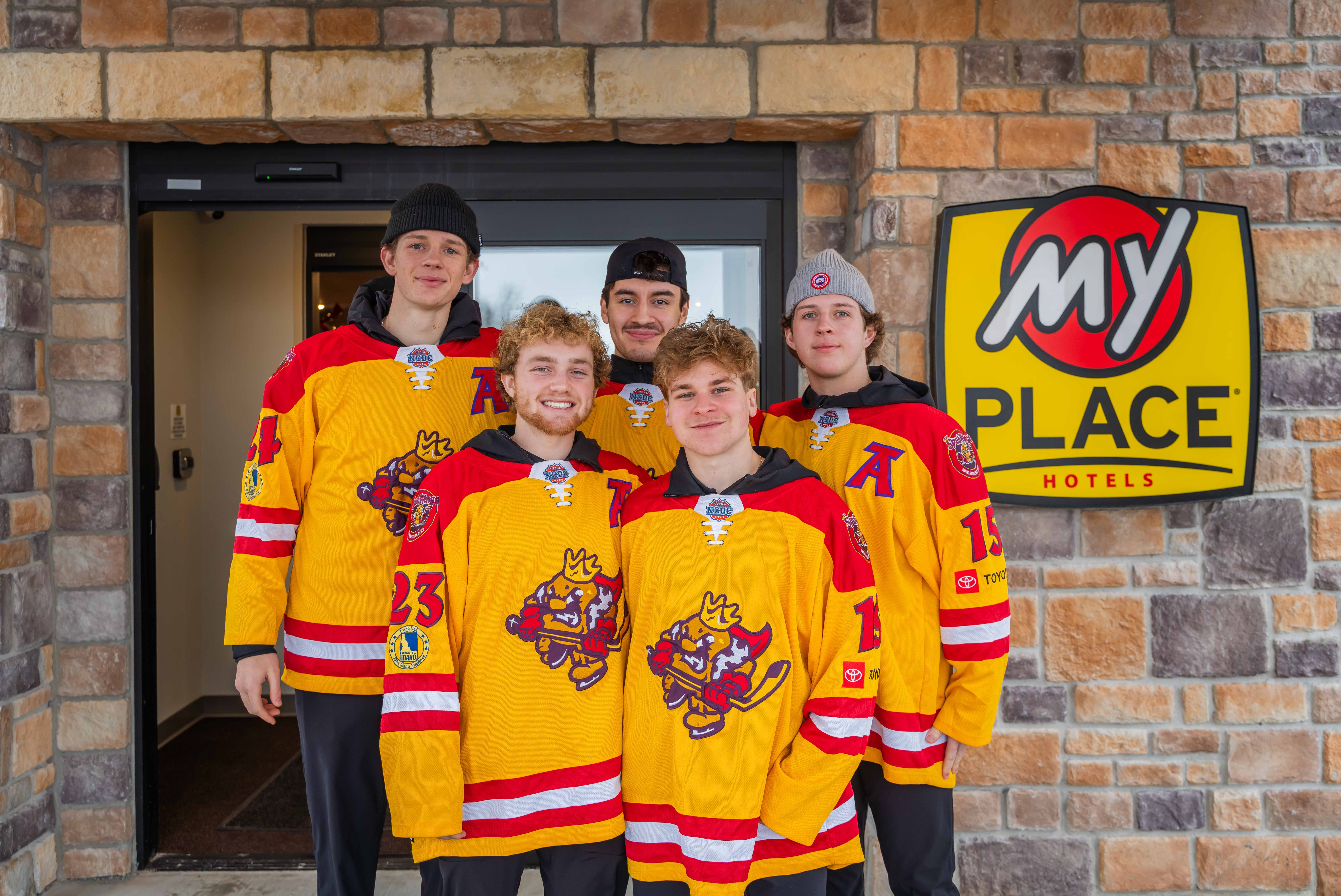 A group of hockey players standing outside of a My Place Hotel