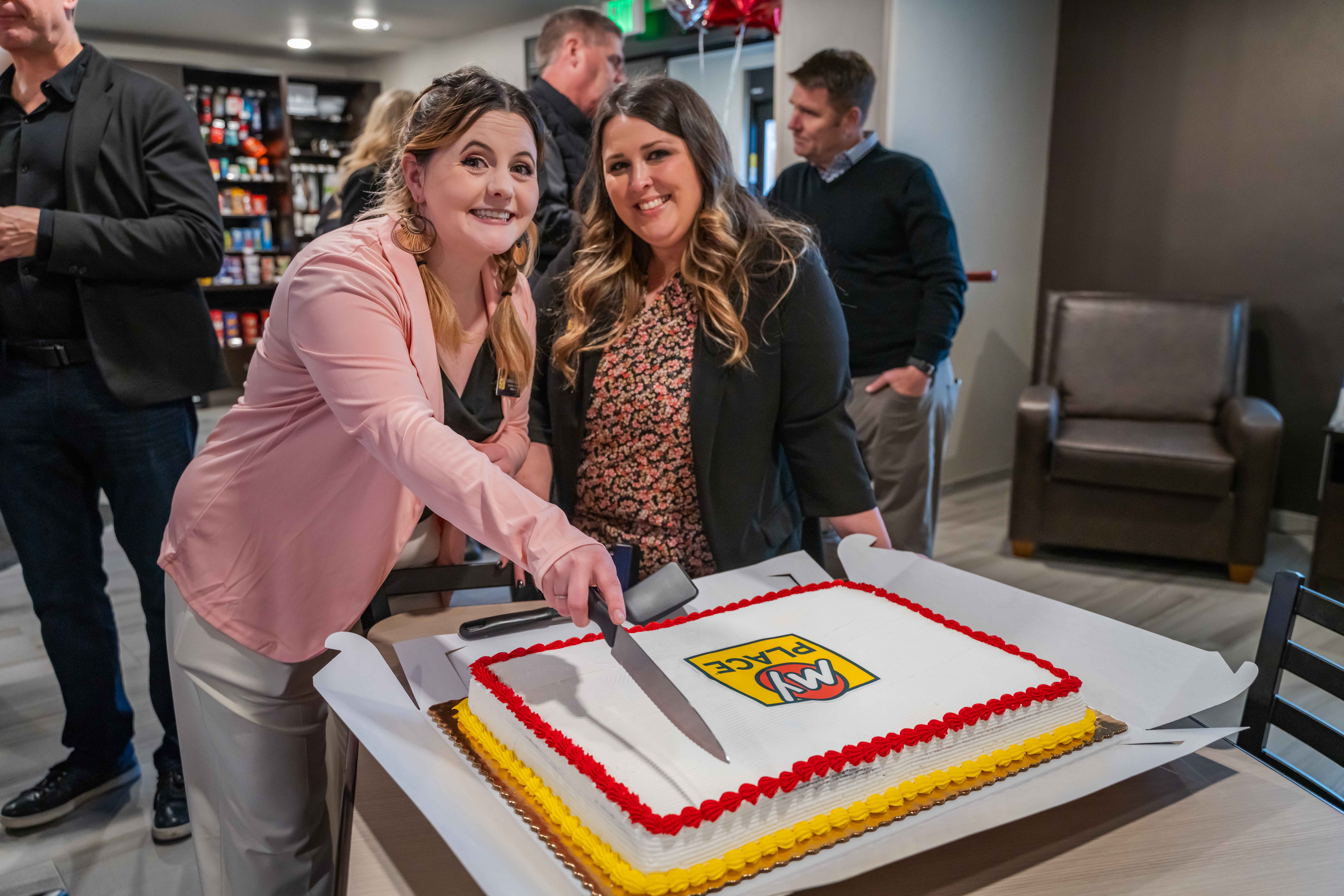 Two women cutting a cake