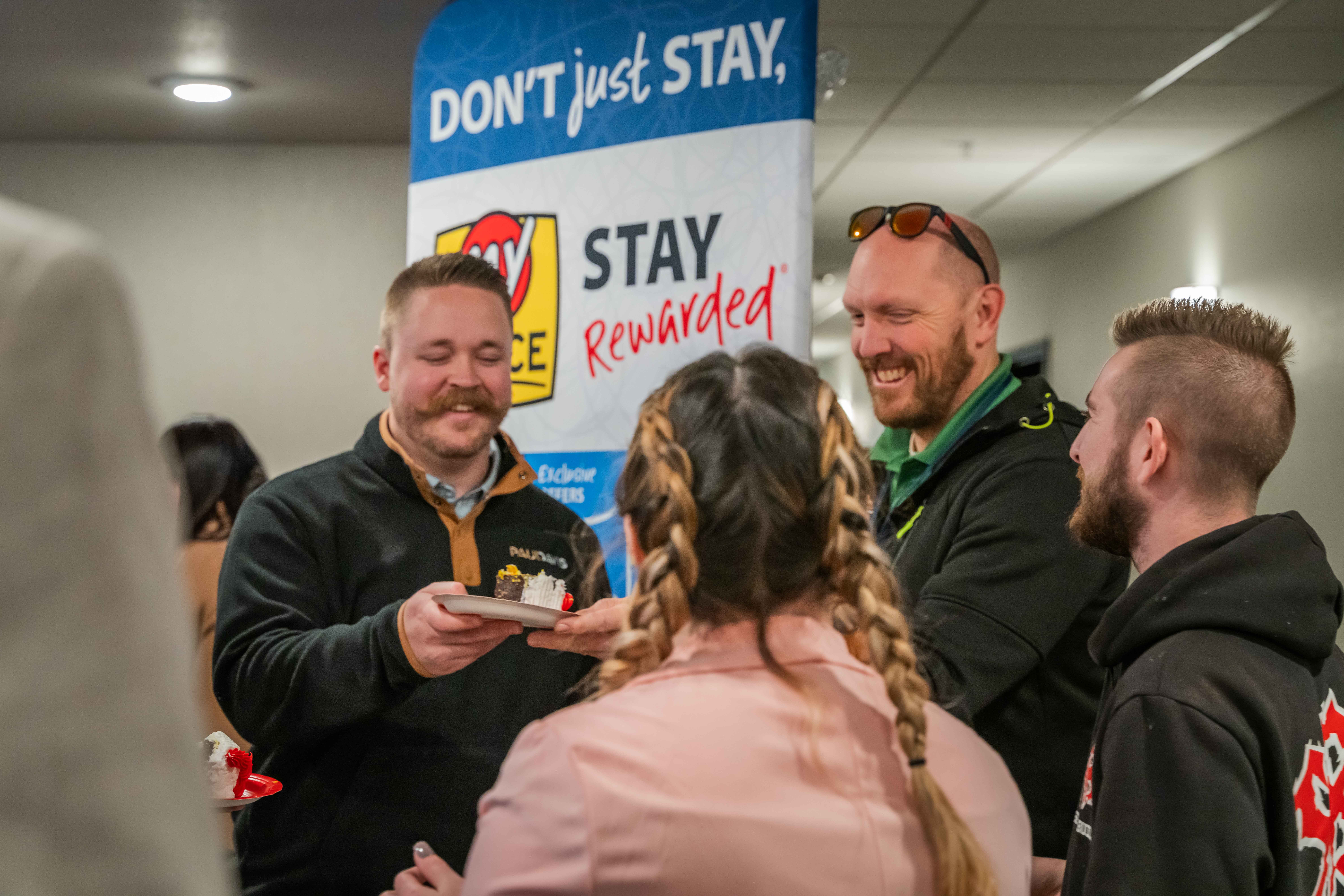 A group of people eating cake during a grand opening celebration