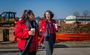 Pictured are two attendees in red coats walking while talking outside at the groundbreaking.