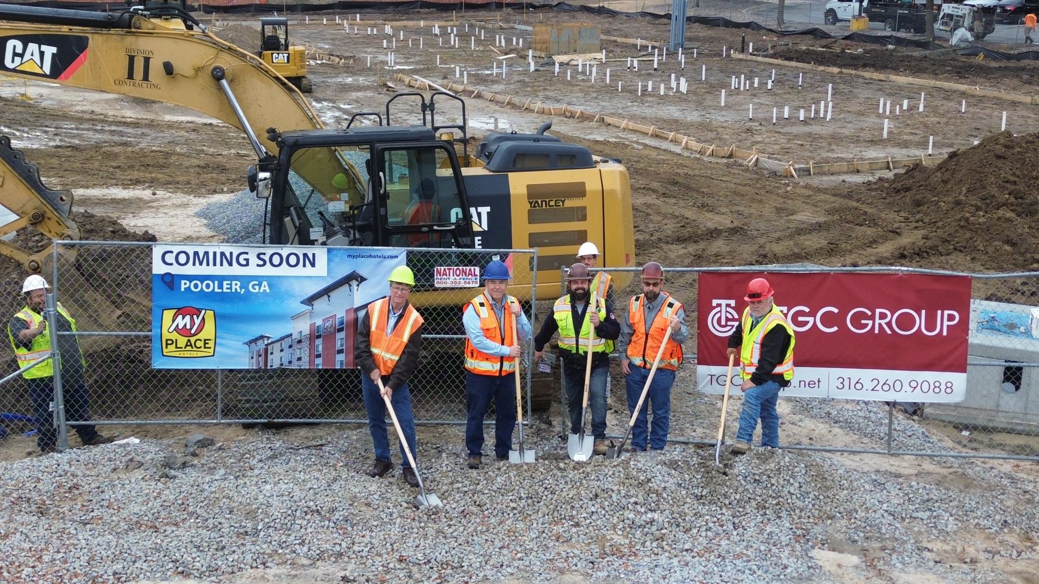 A group of 5 men posing for a groundbreaking photo at a construction site