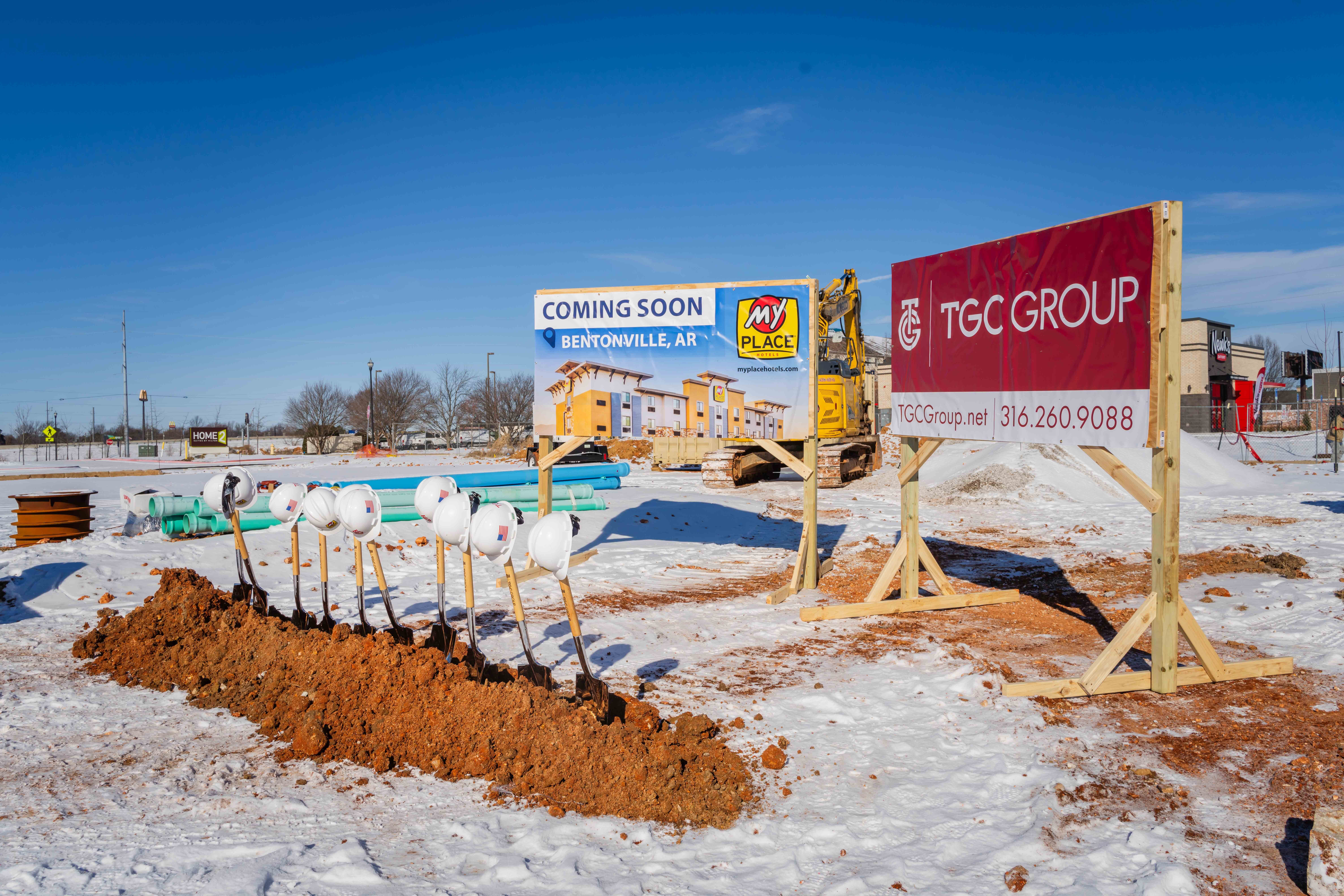 the setting of a groundbreaking event with shovels, hard hands and construction signs