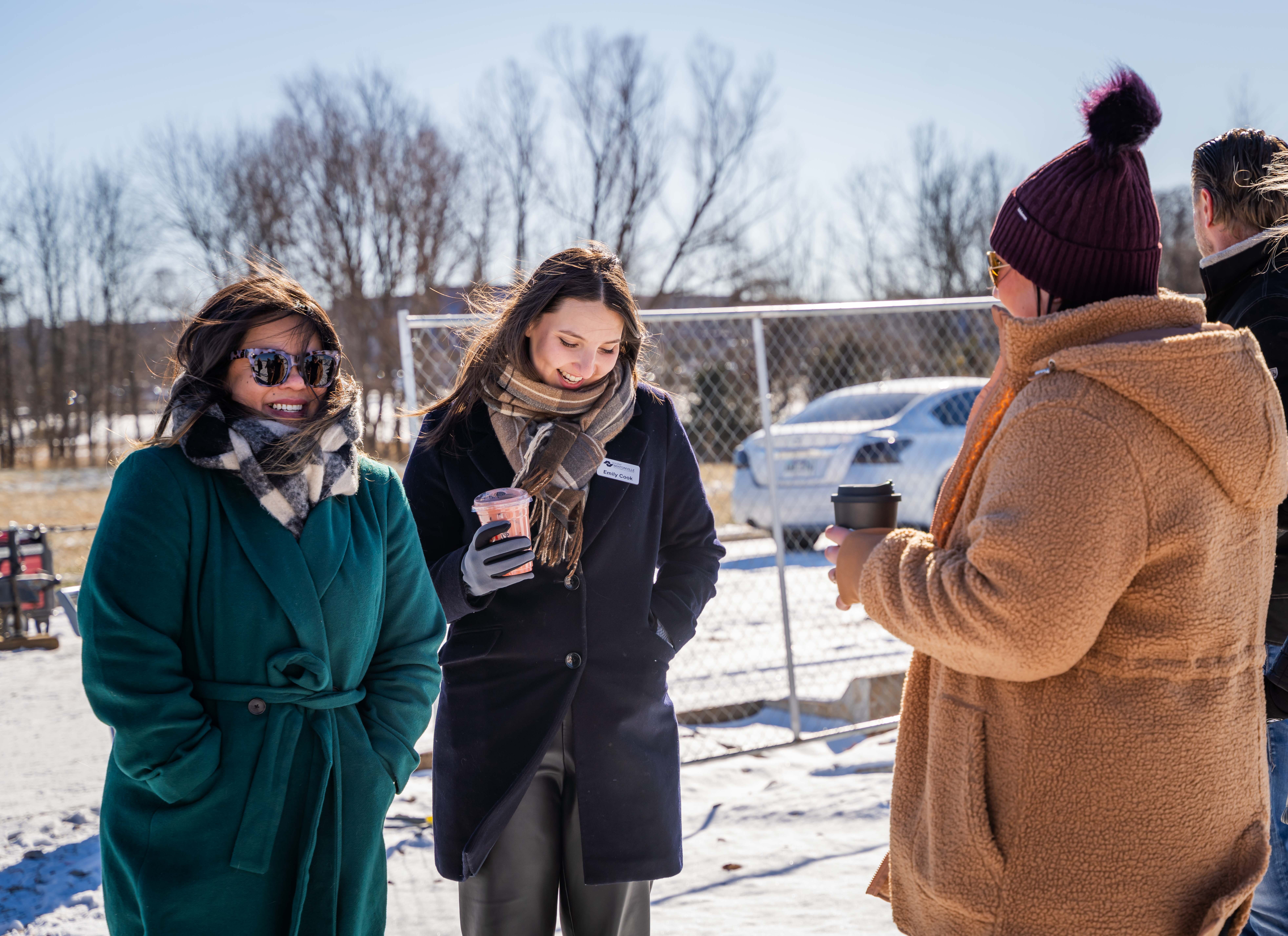 a group of three women laughing and drinking coffee