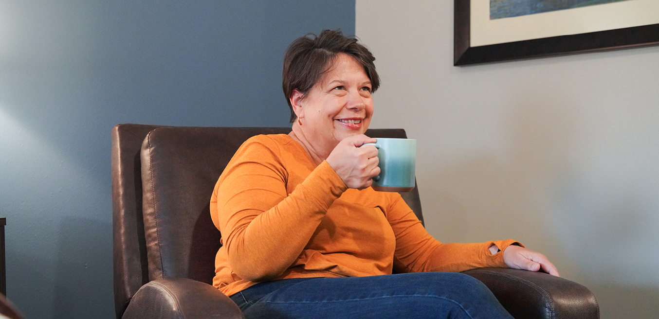 A woman relaxes in a My Place recliner while holding a cup of coffee.