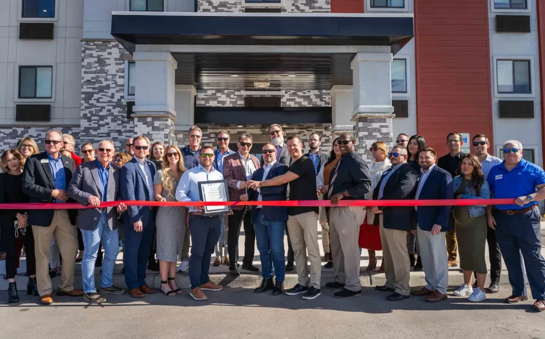 Large group ready to cut a red ribbon outside the hotel entrance in Tucson, Arizona.