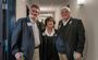 Three people smile for the camera inside a hallway during the hotel's grand opening celebration.