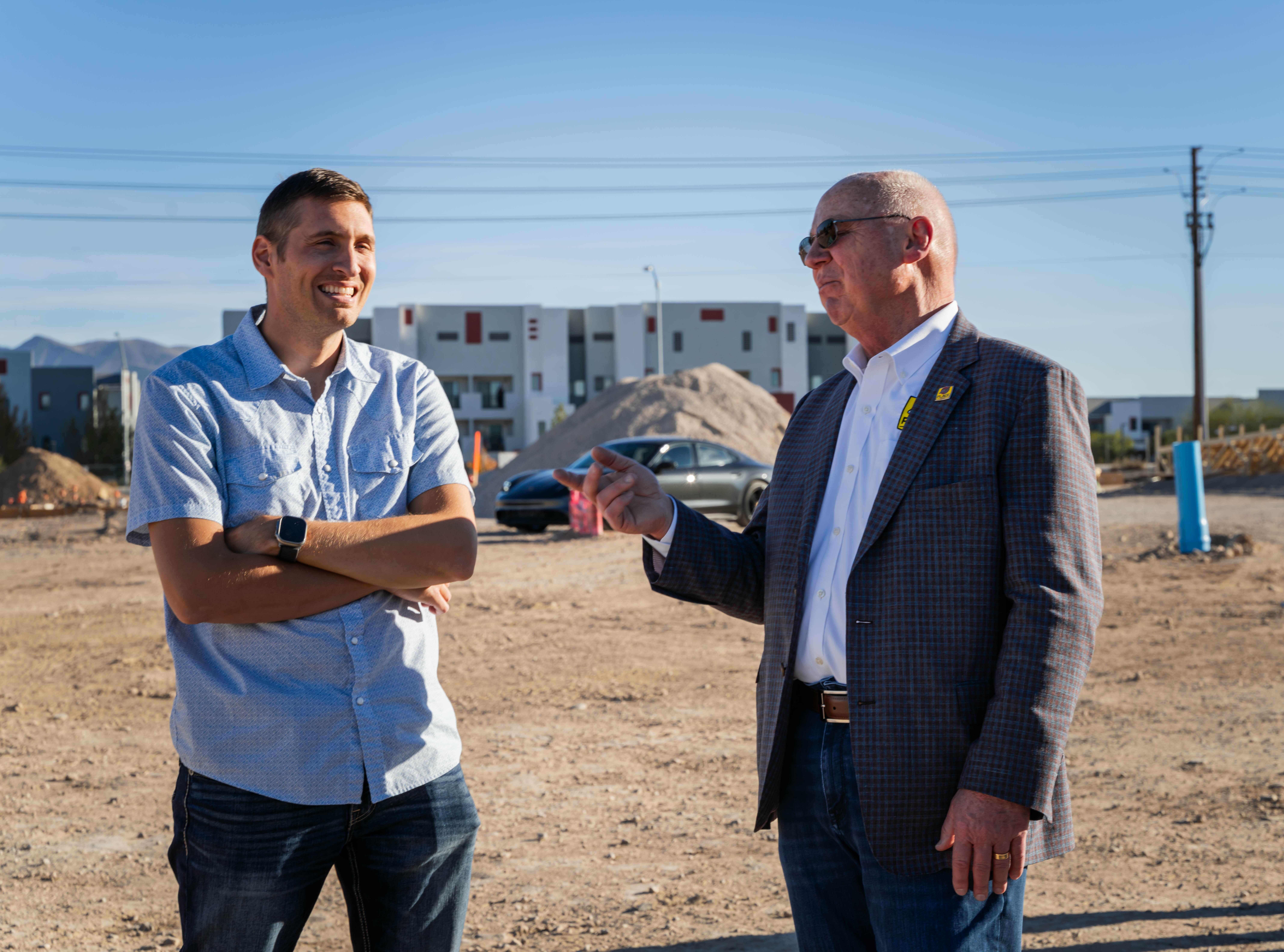 Two people standing and talking at groundbreaking construction site.