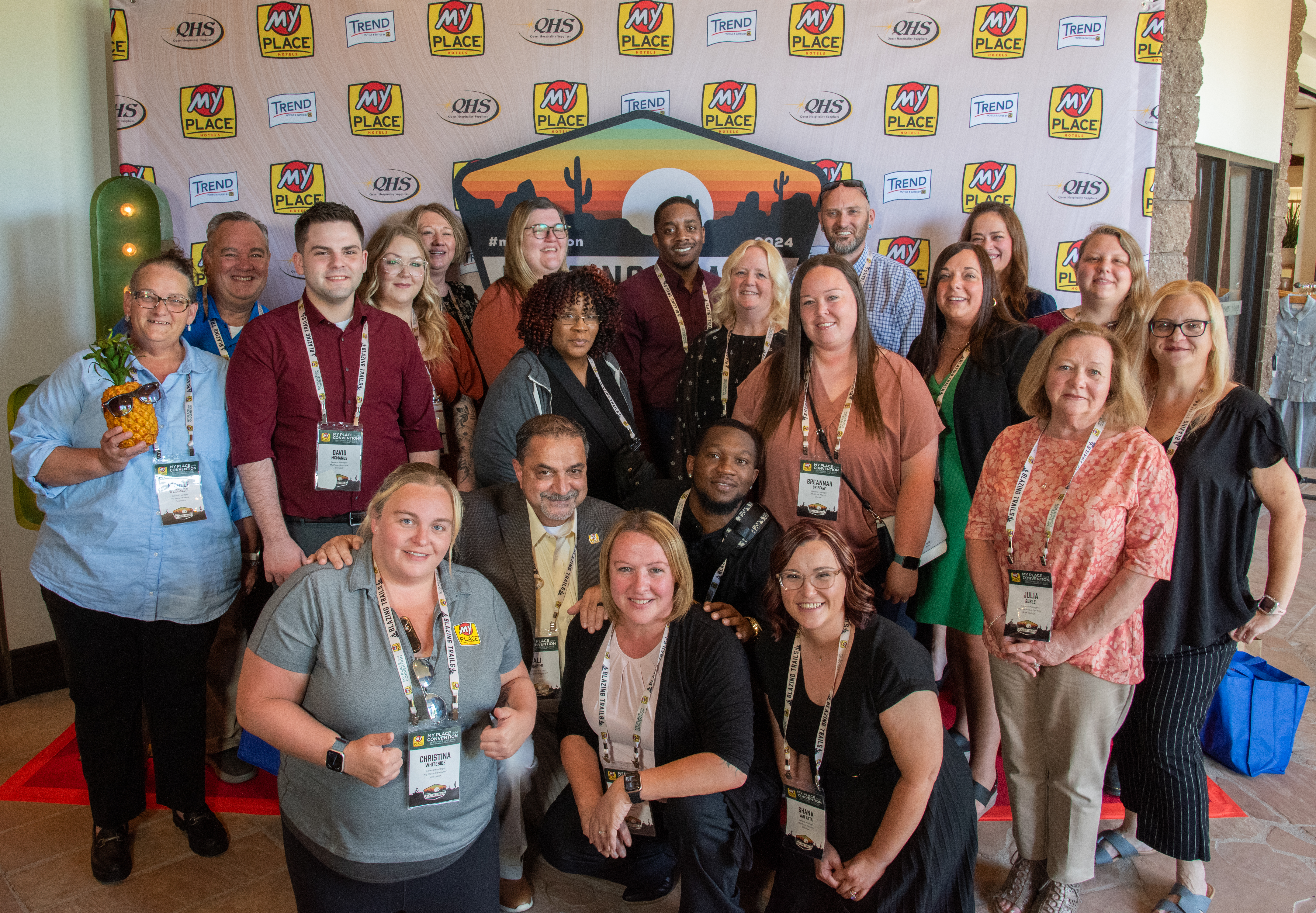 A group of people posing in front of a backdrop at a hospitality conference