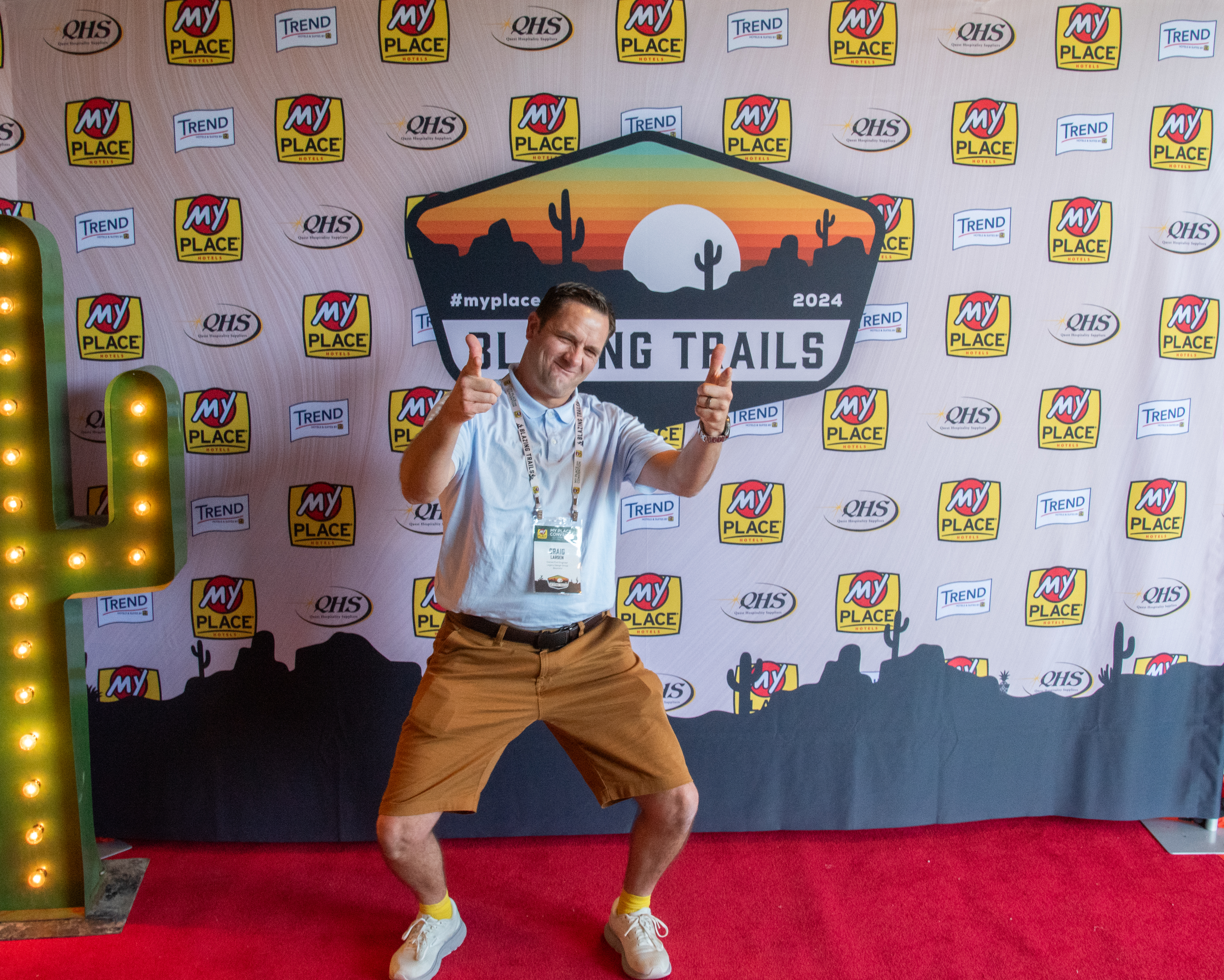 A man posing in front of a backdrop at a hospitality conference