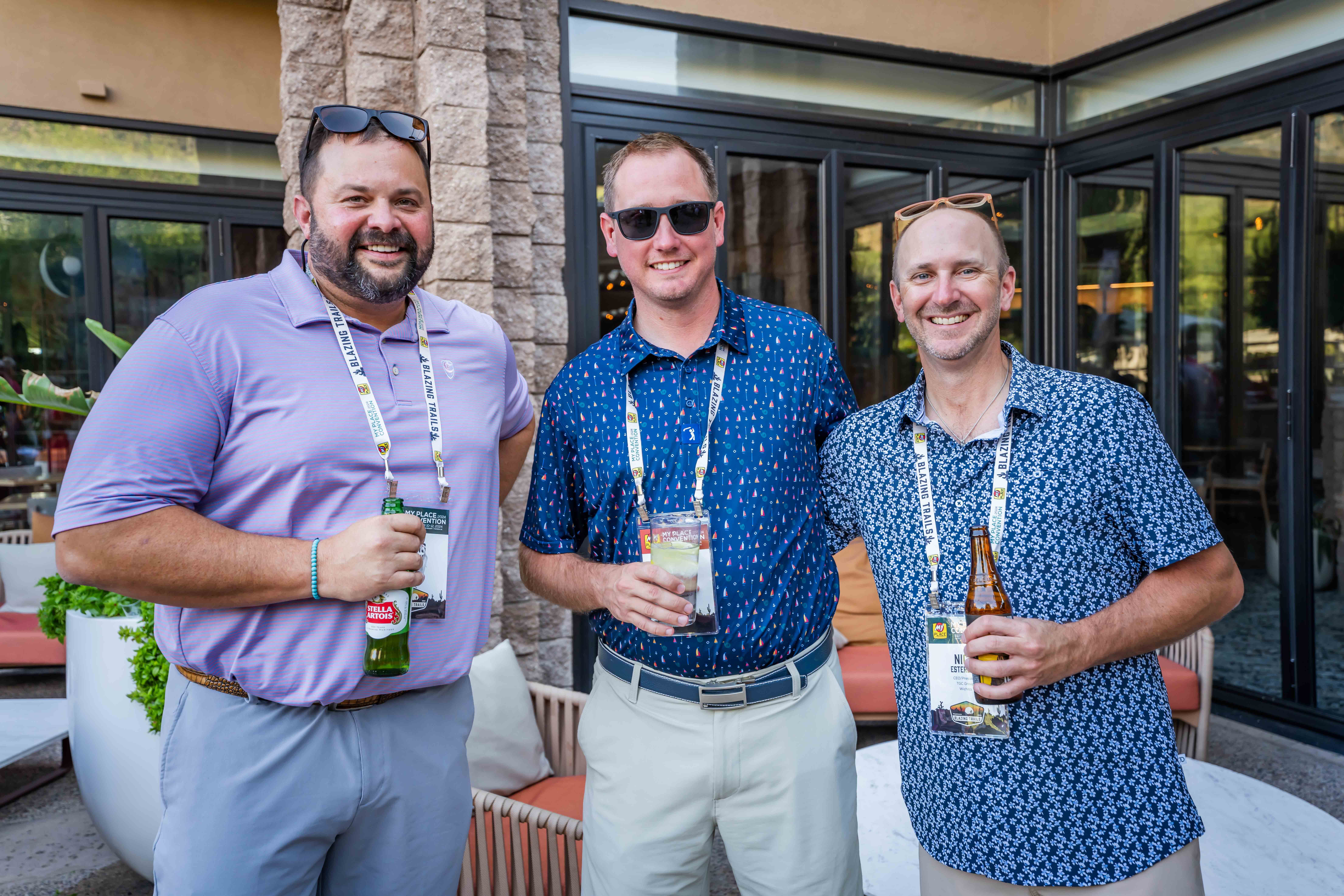 Three men with drinks posing for a photo