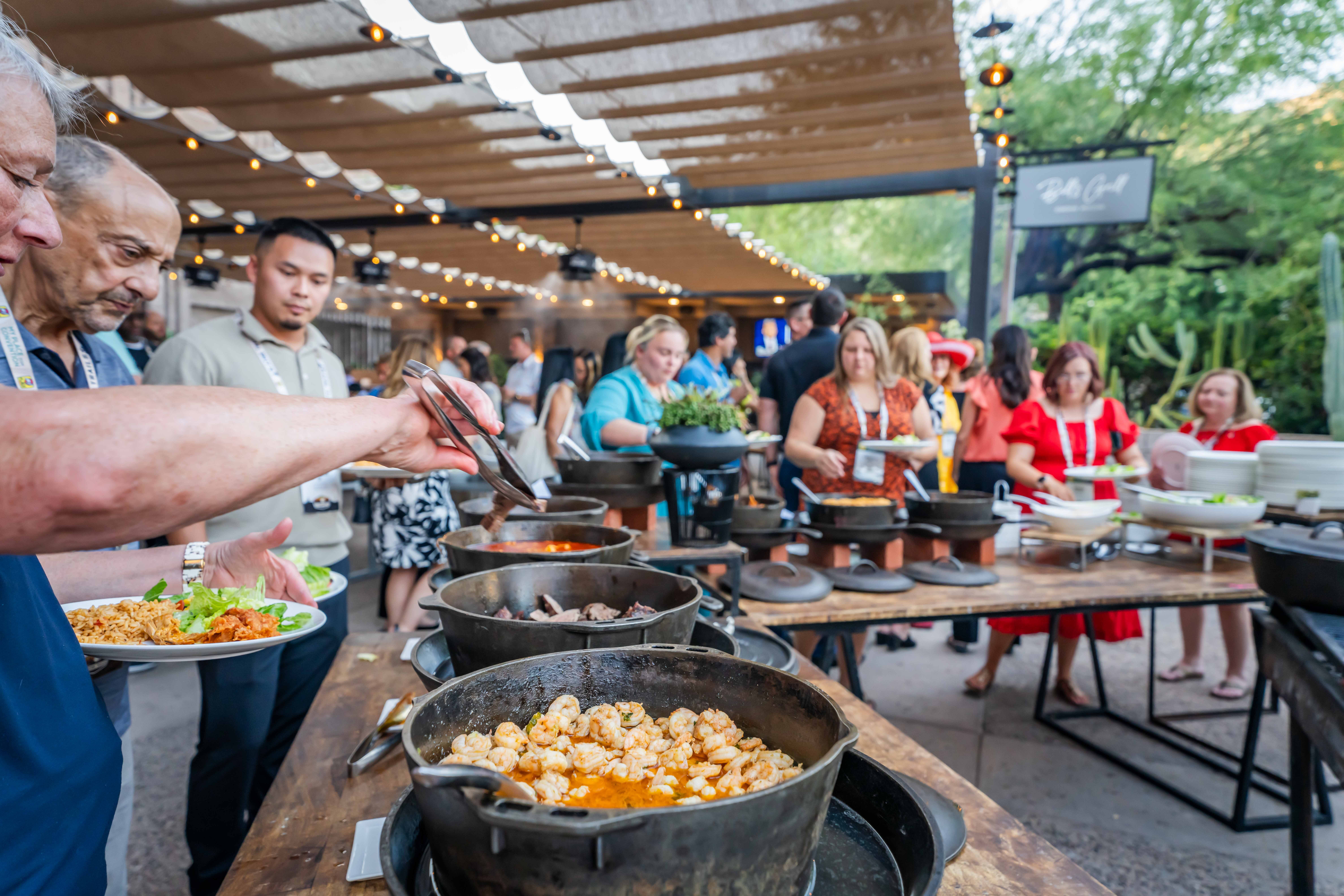 A line of people getting food in an outdoor buffet line