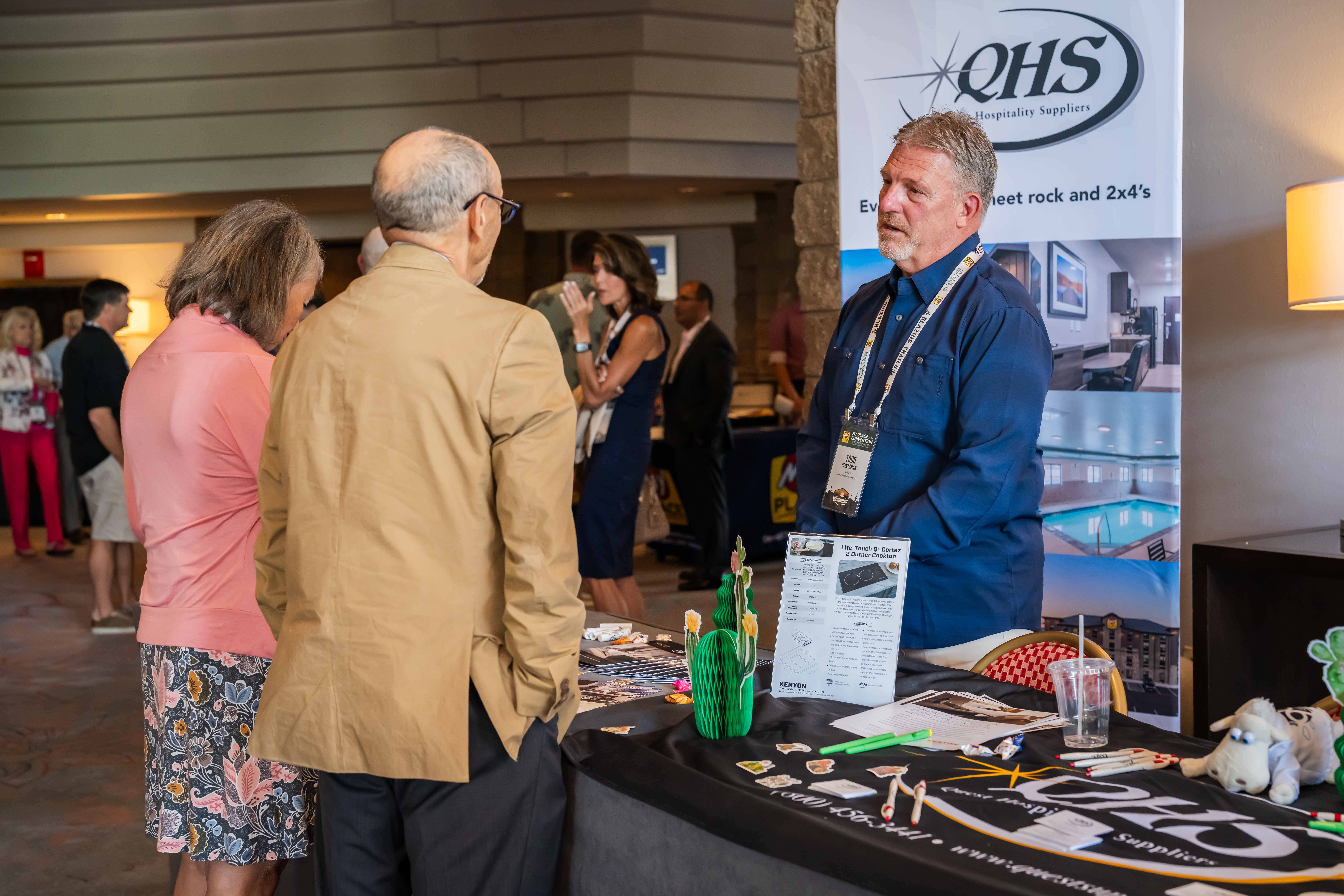 A vendor interacting with a couple at a tradeshow