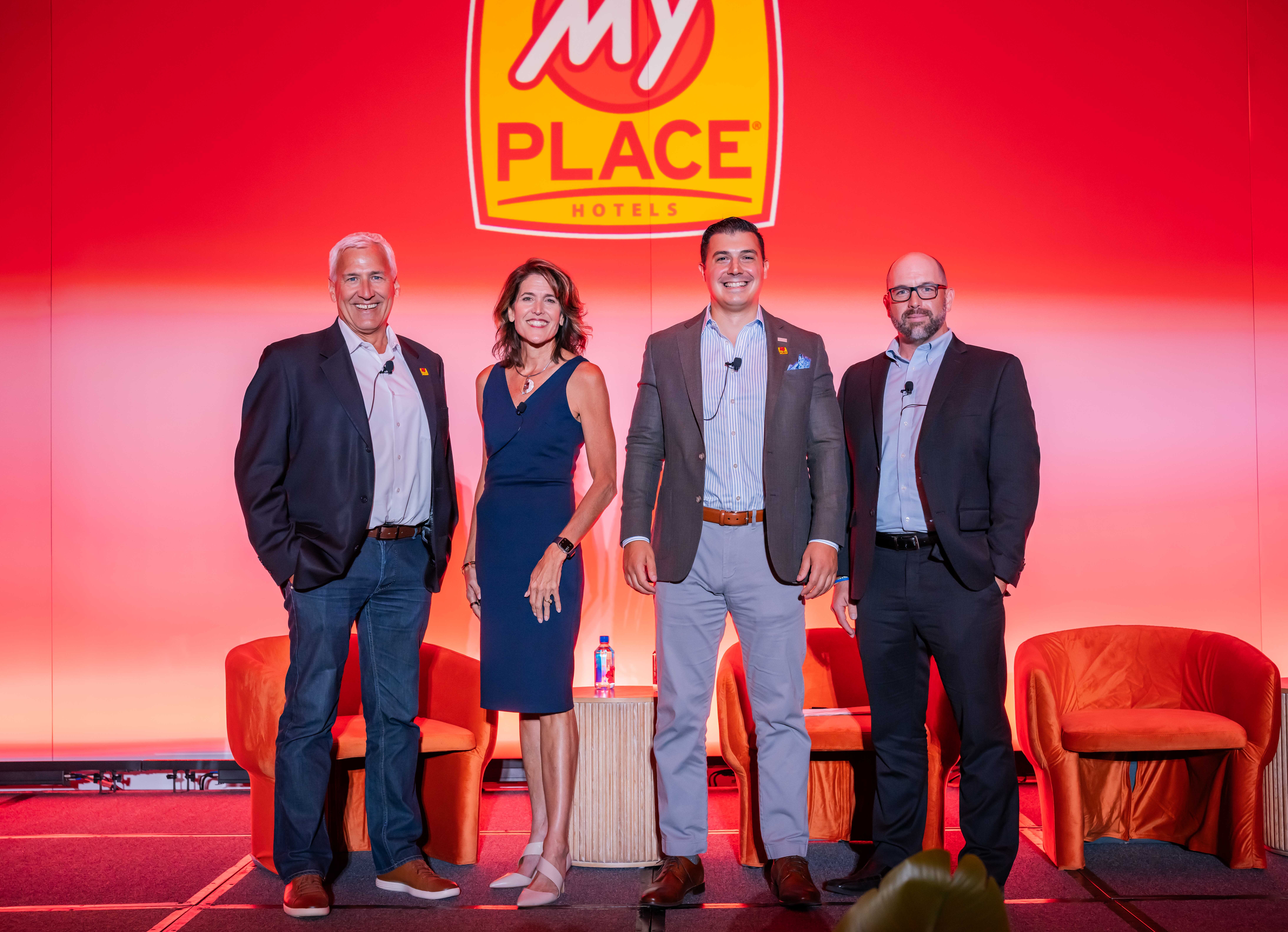 Four individuals on stage smiling for a photo