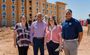 Four professionals pose in front of the unfinished My Place hotel in Mesa.