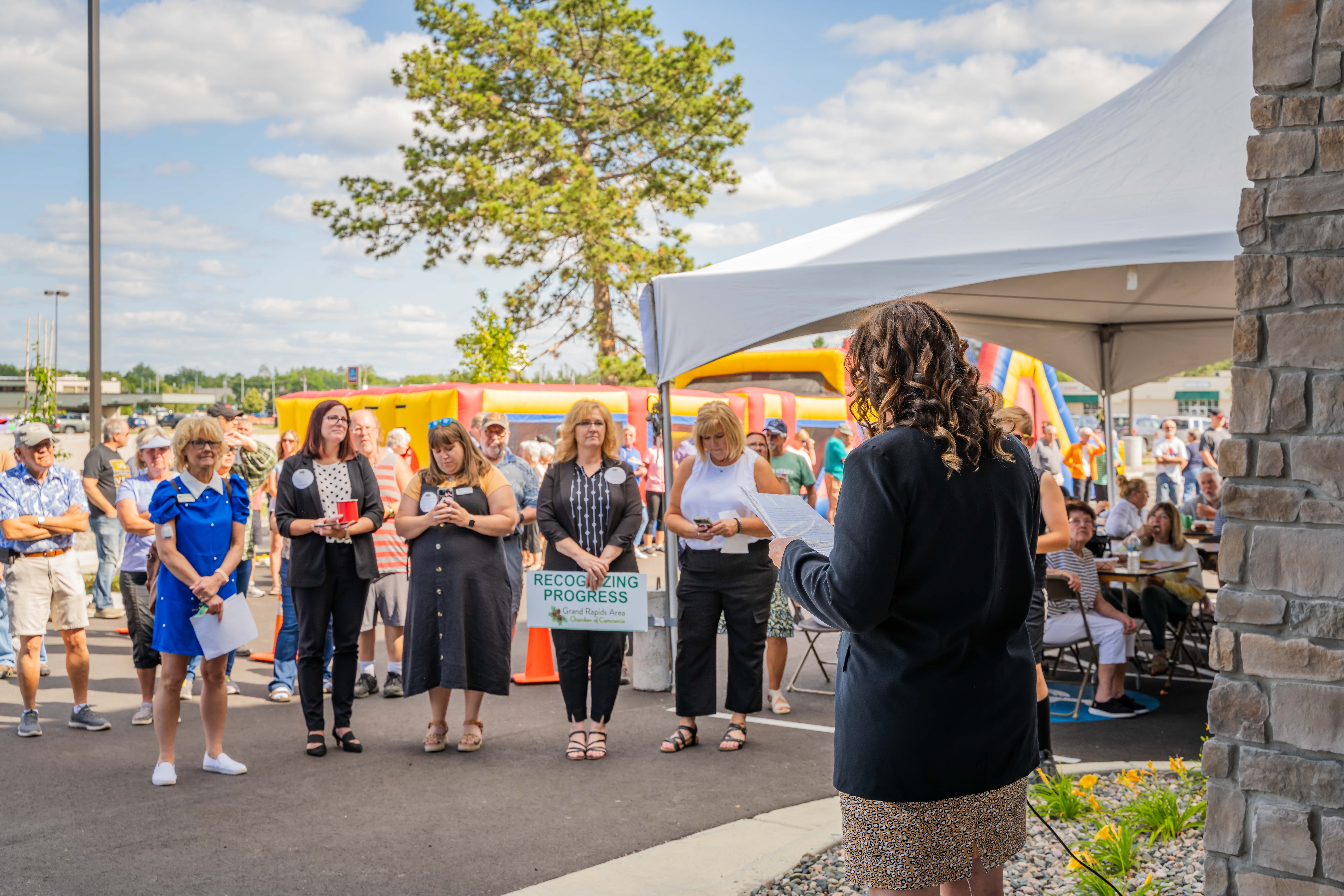 A woman speaking outside a hotel at a grand opening celebration.