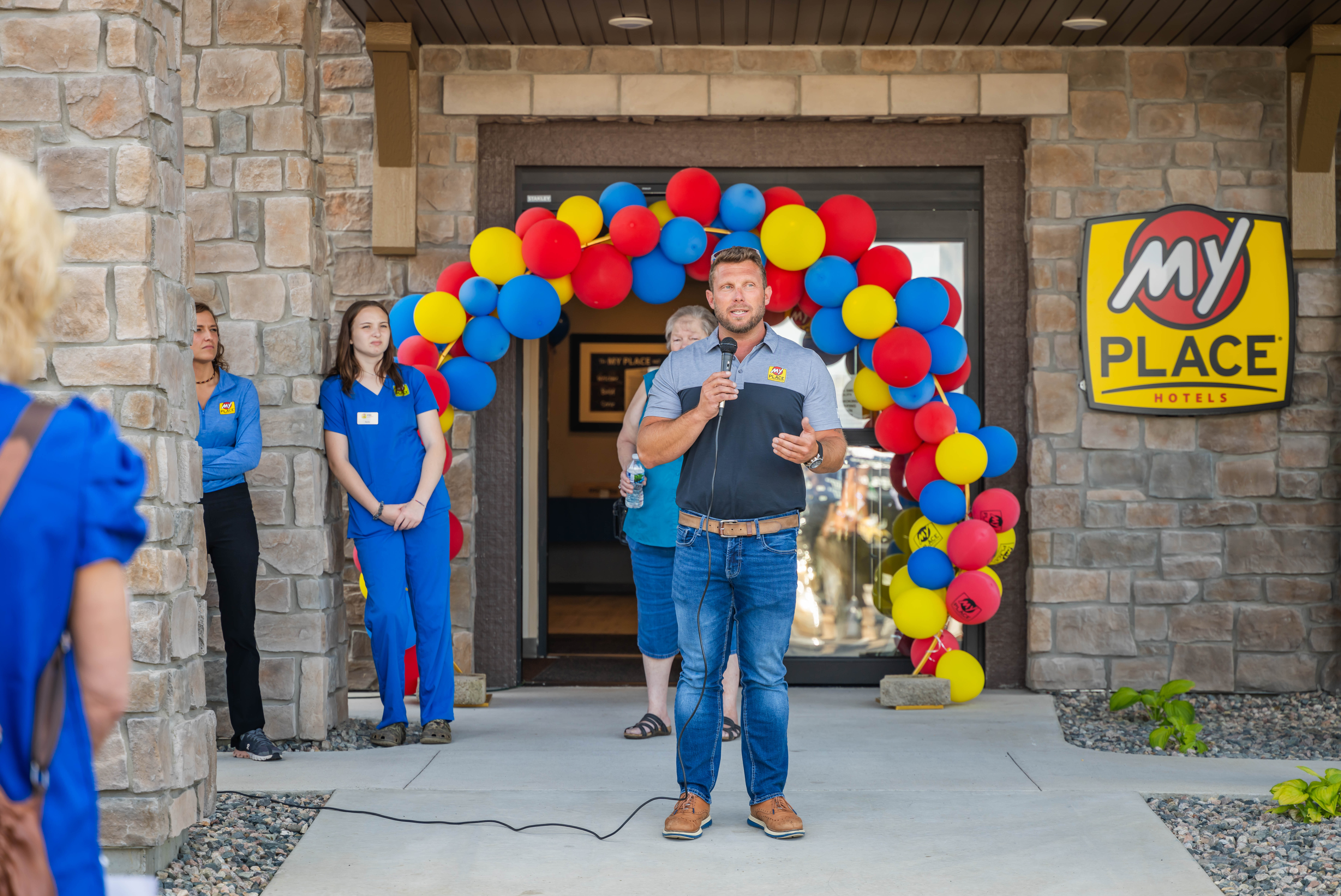 A man speaking at a grand opening celebration for a new hotel.