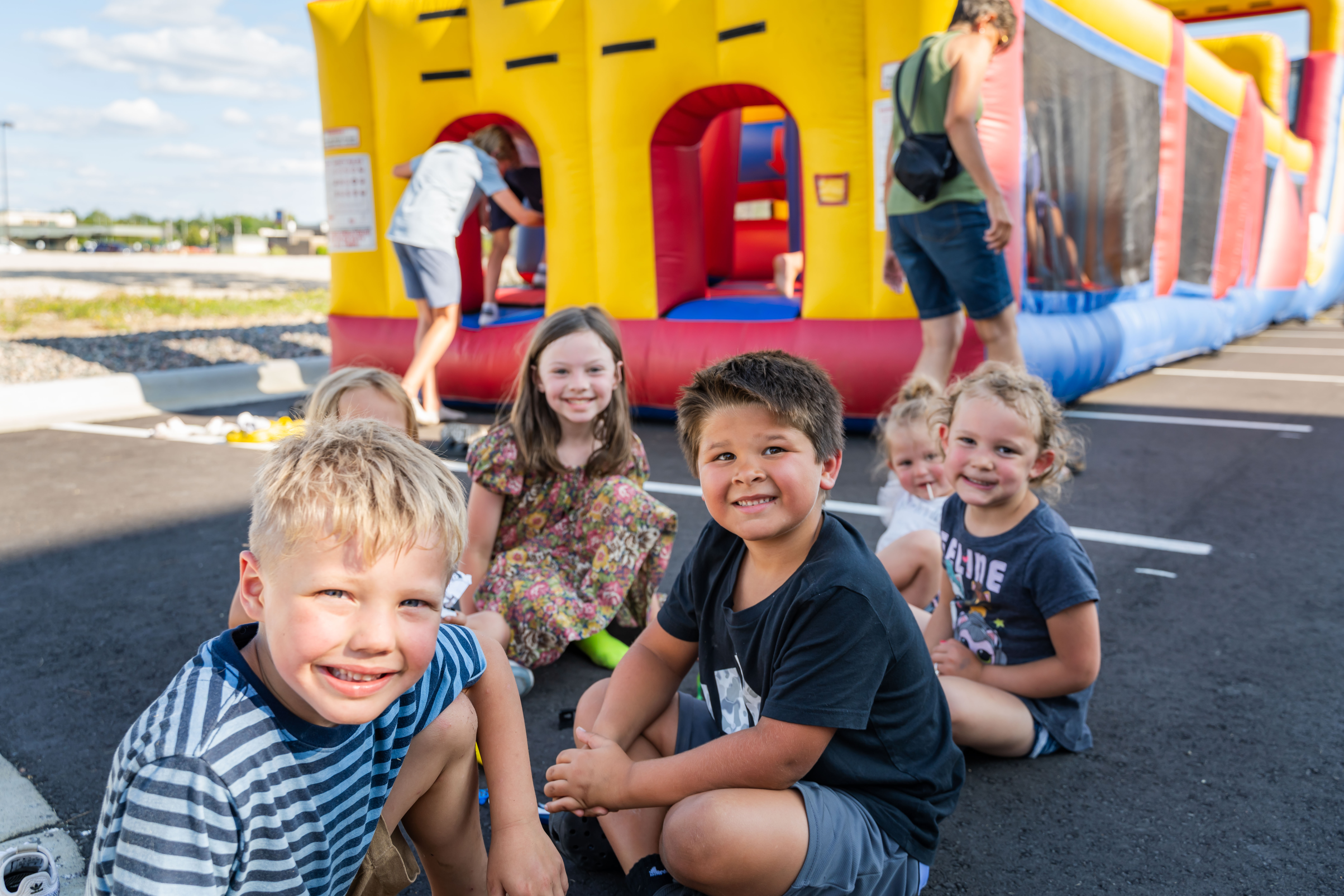 Kids smiling next to a bouncy house.