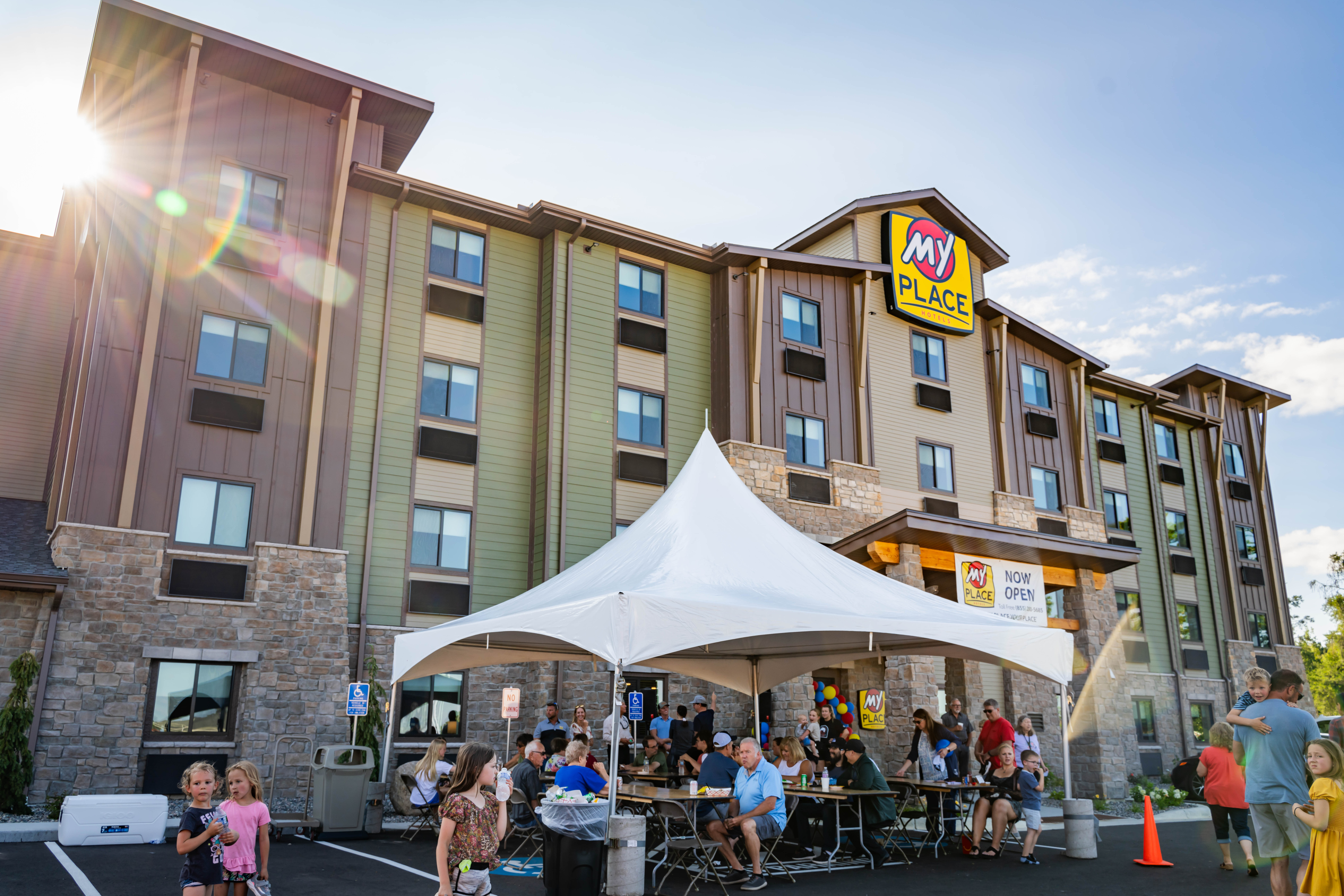 An exterior picture of a My Place Hotel during a grand opening celebration