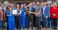 A group of attendees are pictured holding the large scissors used for cutting the ribbon at the grand opening.