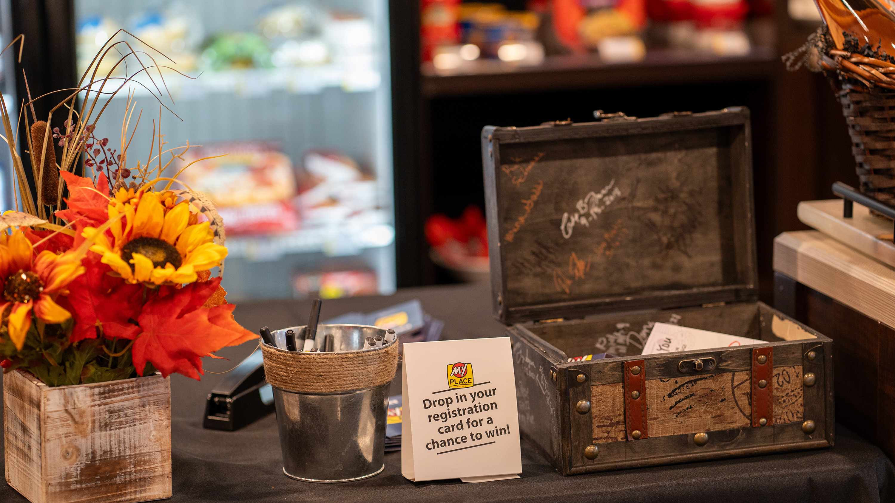 Flowers, pens, and brown box on the front desk during the grand opening celebration.