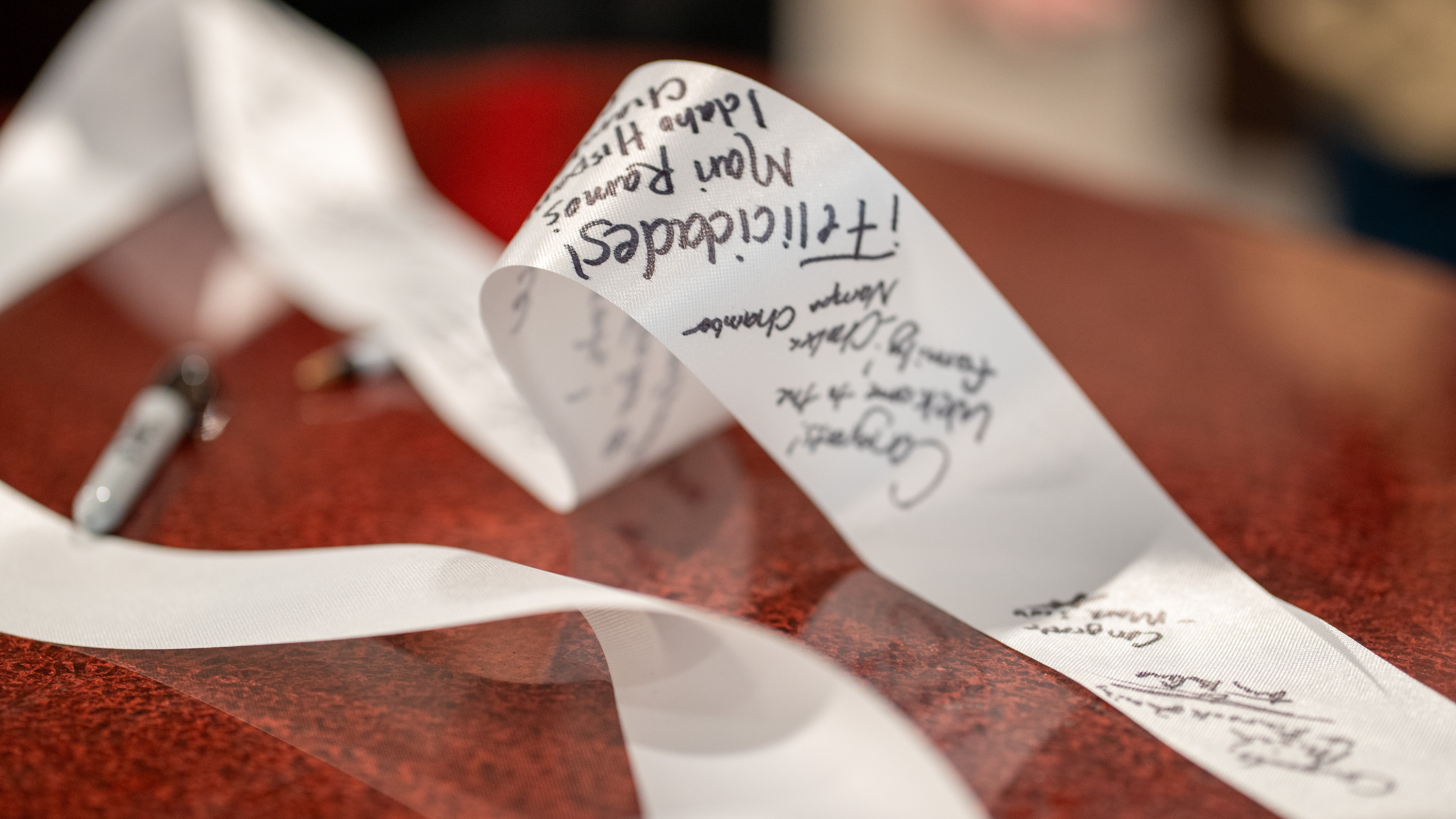 A white ribbon filled out with signatures.