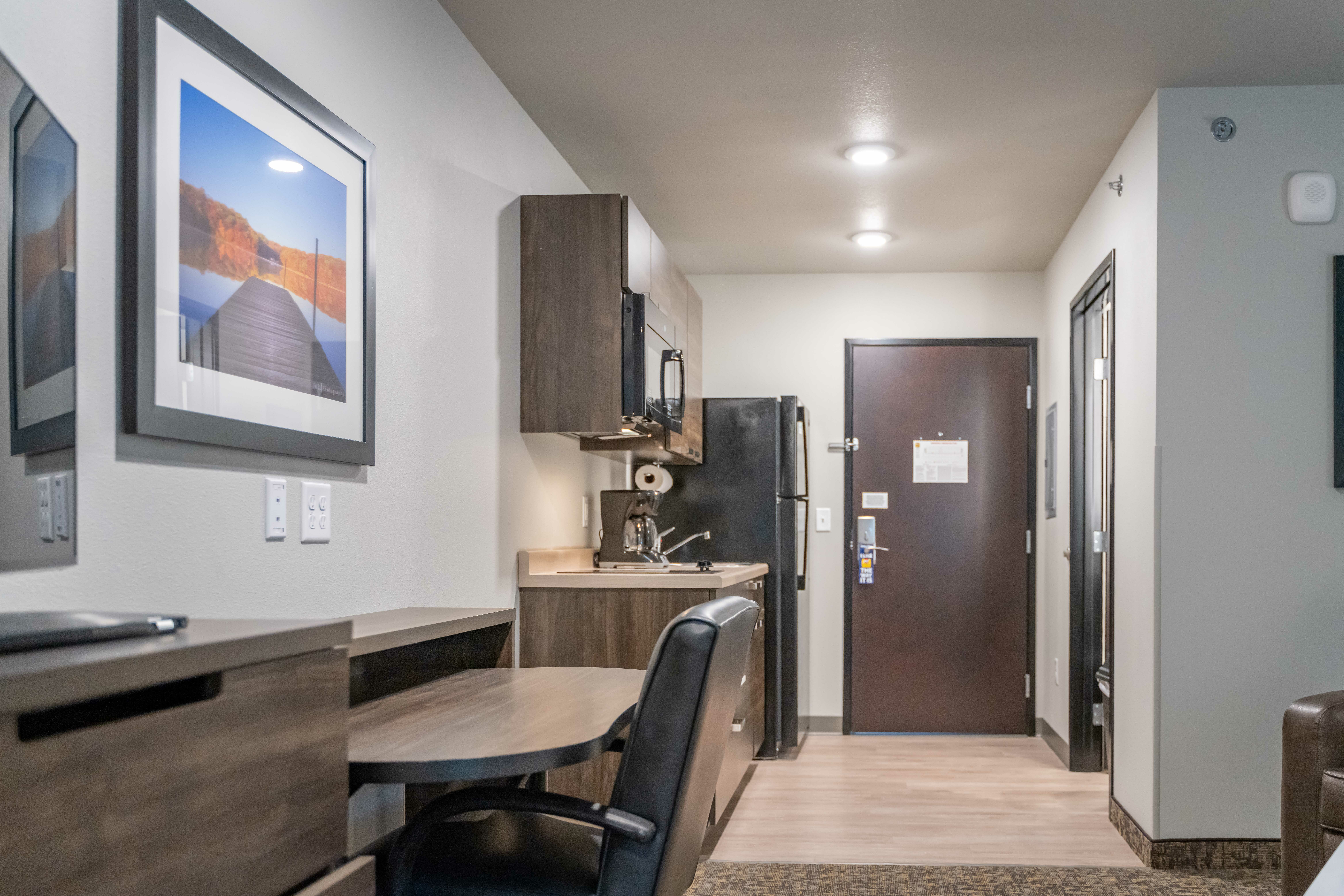 Interior of hotel room showing desk, kitchenette and front door.