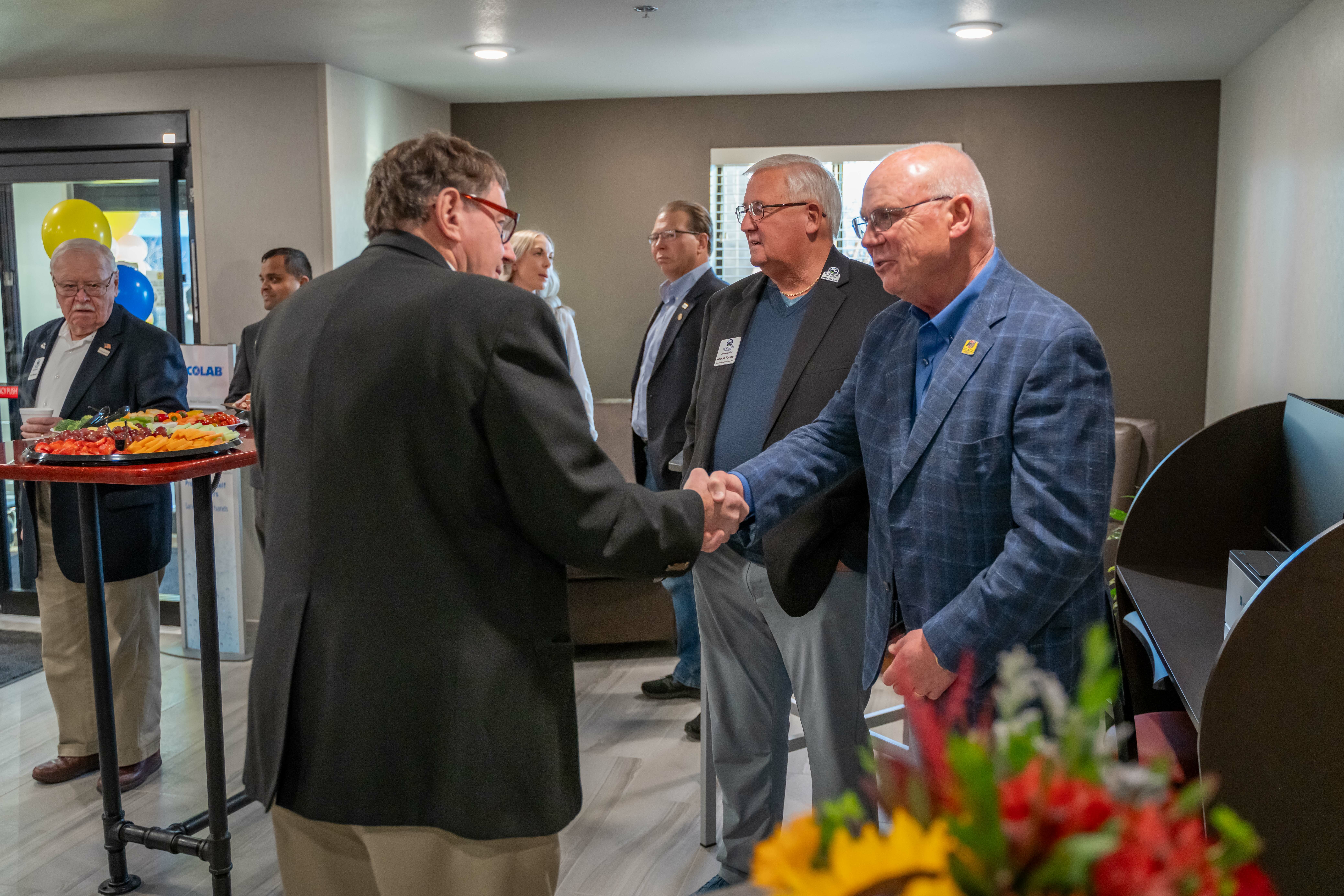 Two men shake hands while other look on during the grand opening ceremony inside the hotel lobby.