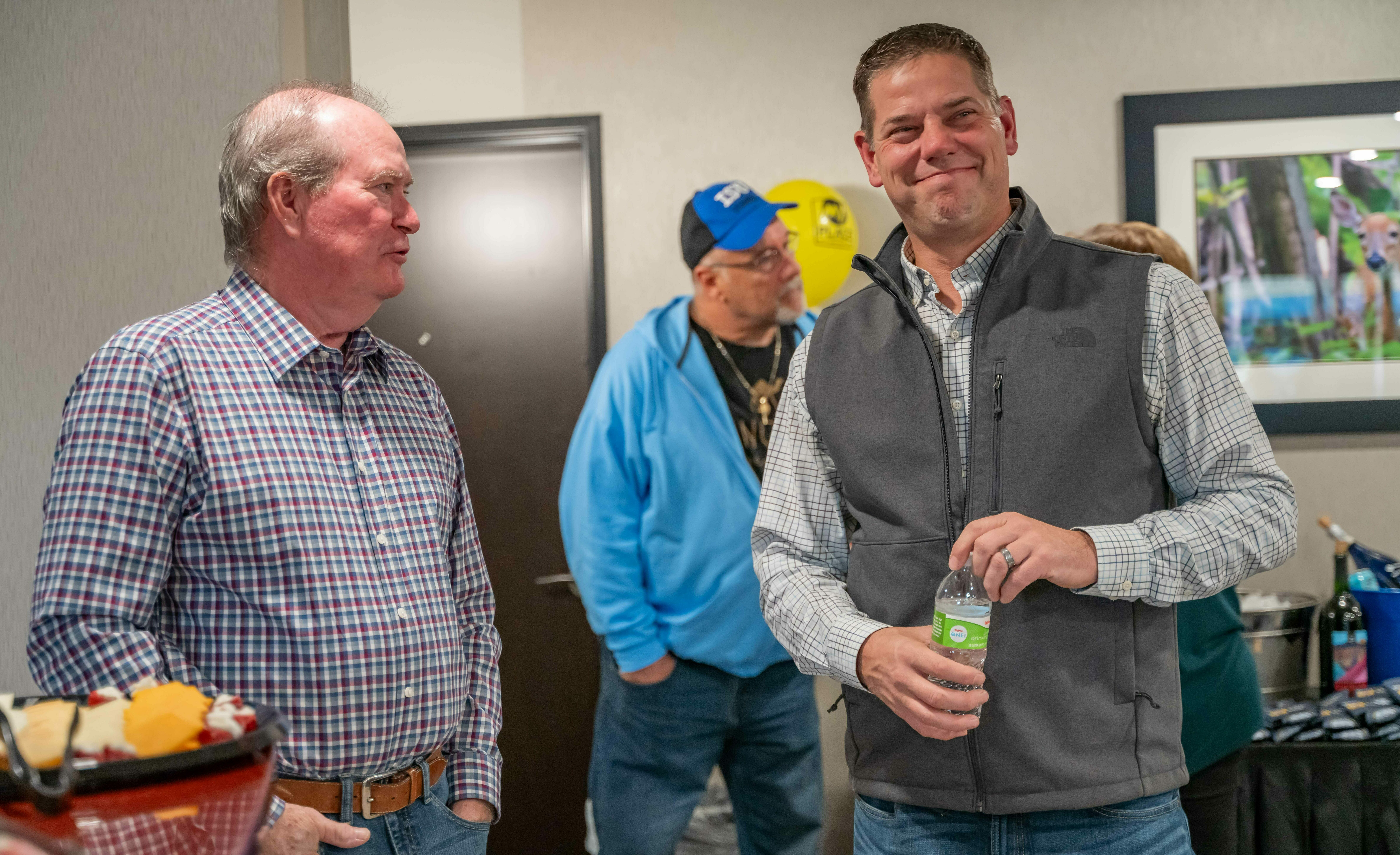 Two men stand and smile inside the lobby at the hotel's grand opening celebration.