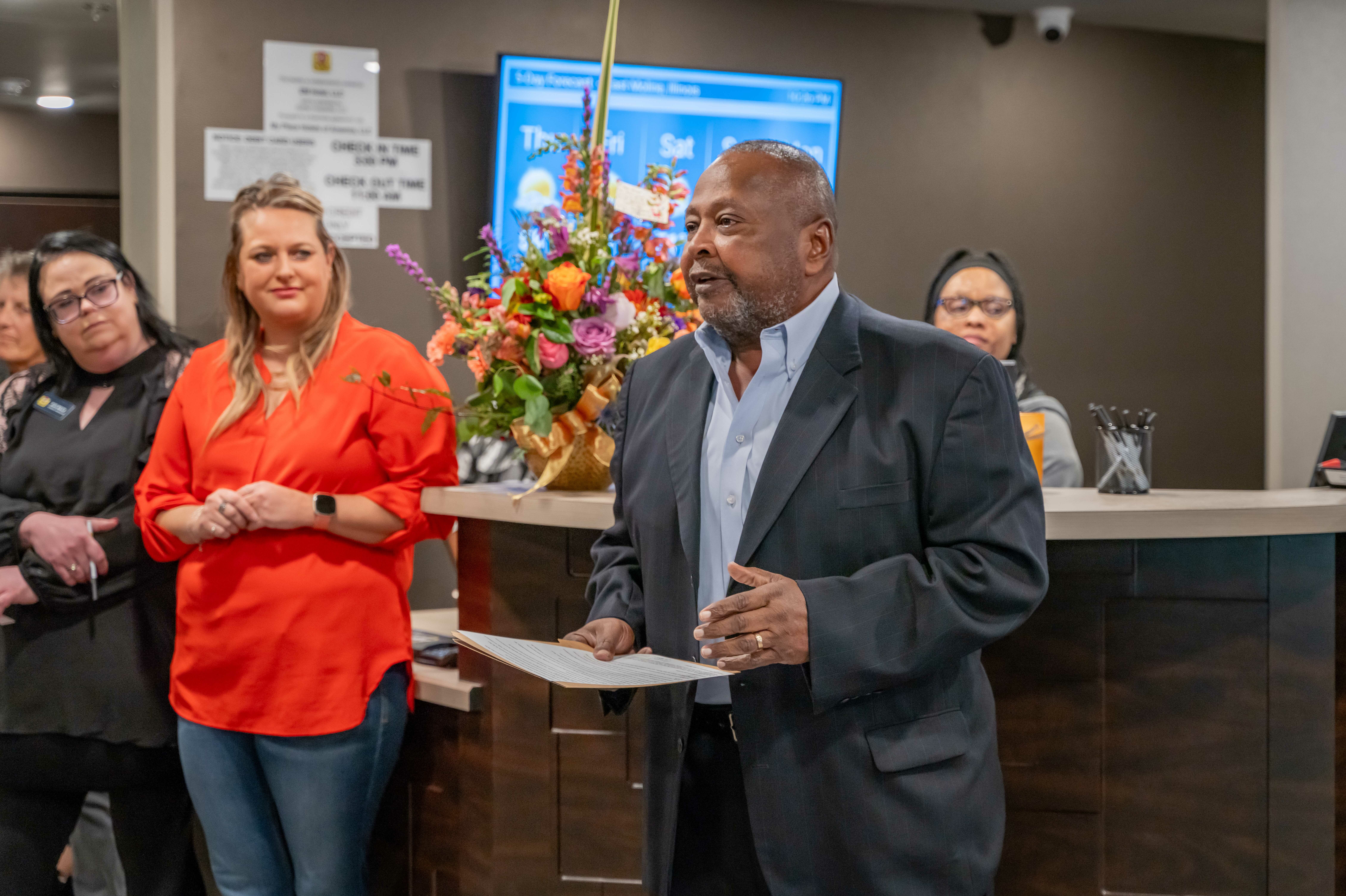 The Mayor of East Moline addresses a group of people inside the lobby during the hotel's grand opening celebration.