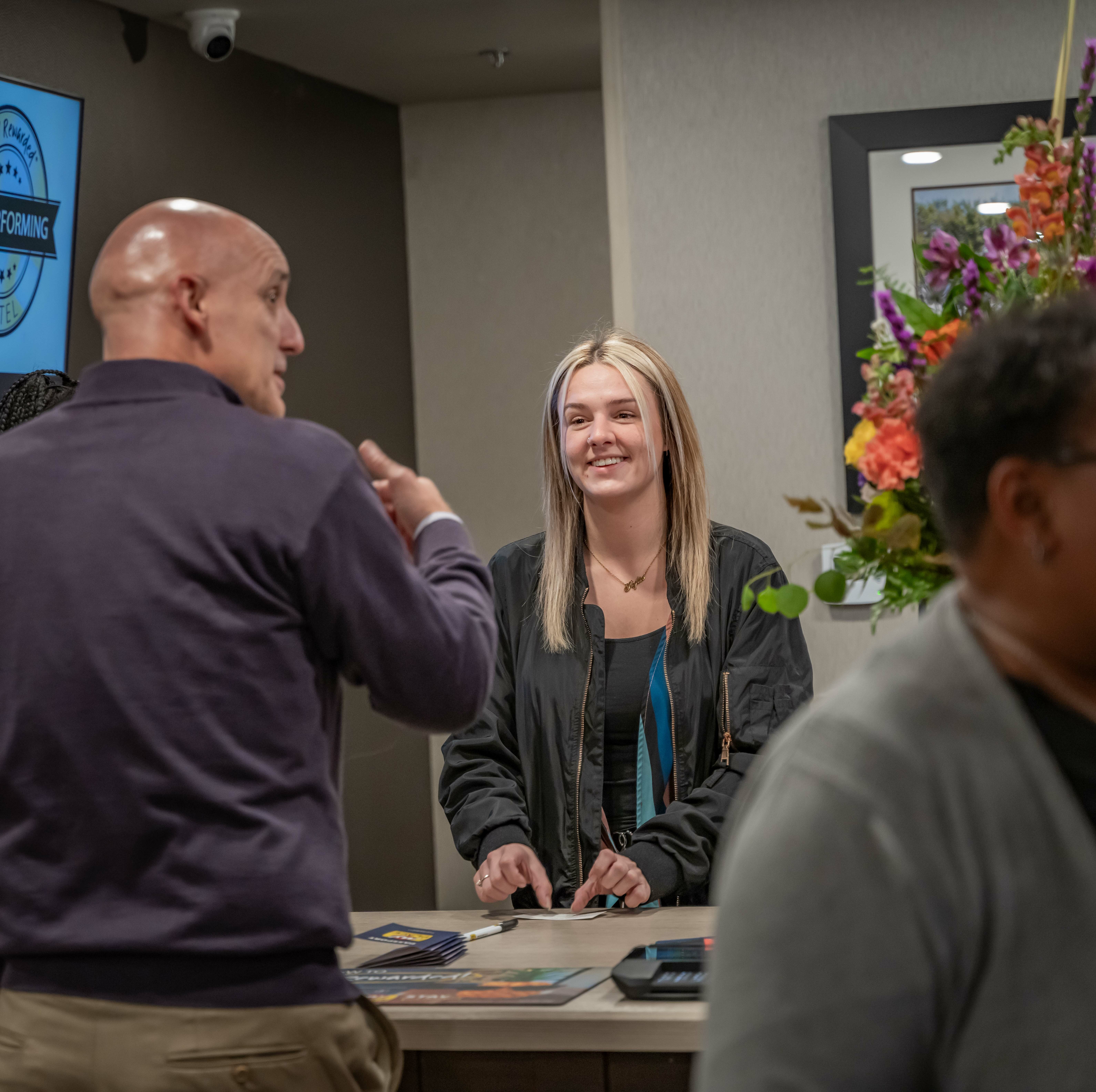 Front desk worker smiling at a man during the grand opening ceremony inside the hotel lobby.
