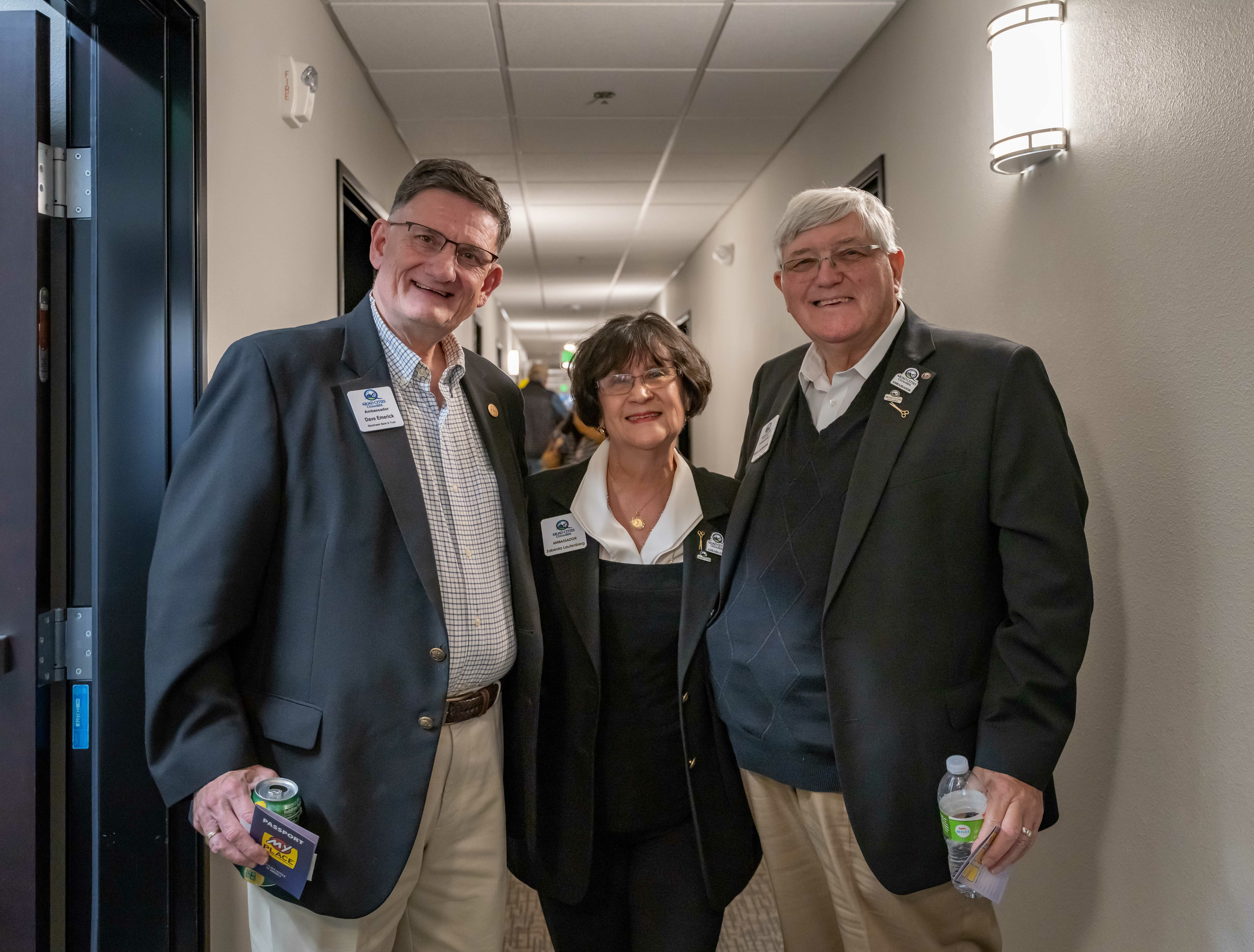 Three people smile for the camera inside a hallway during the hotel's grand opening celebration.