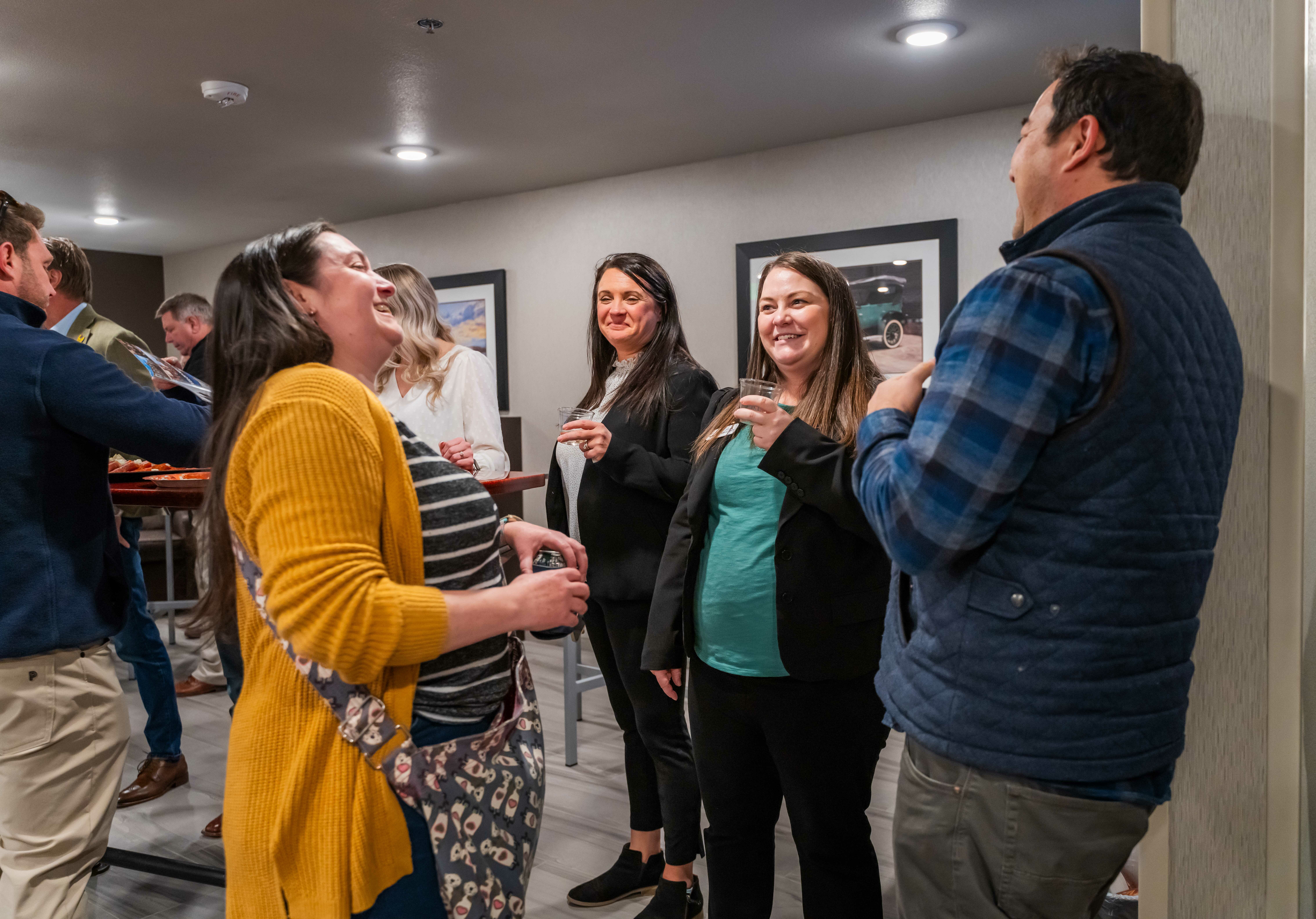 A group of four people stand in a circle laughing during the grand opening celebration inside the hotel's lobby.