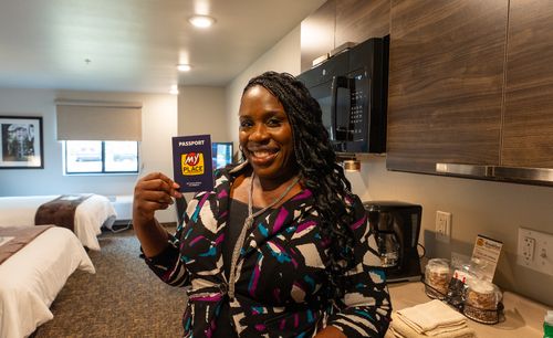 A guest is pictured holding up a My Place card in one of the new guest rooms.
