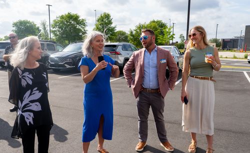 Guests are pictured having conversations in the parking lot of the new hotel, including the president of My Place, Ryan Rivett.