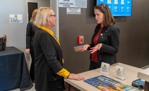 Pictured are two professionals engaging in conversation near the front desk of the new hotel.