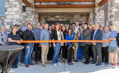 Attendees are pictured posing outside of the new hotel, ready to cut the ribbon for the grand opening.