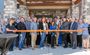 Attendees are pictured posing outside of the new hotel, ready to cut the ribbon for the grand opening.
