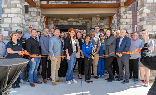 Attendees are pictured standing outside of the new hotel, watching as the ribbon is cut for the grand opening.