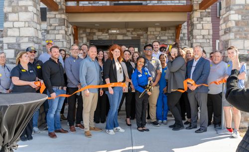 Attendees are pictured standing outside of the new hotel, watching as the ribbon is cut for the grand opening.