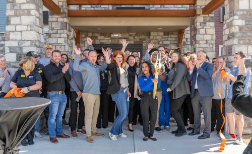 Attendees are pictured celebrating the cutting of the ribbon for the new My Place hotel with arms in the air.