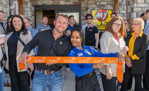 Professionals of My Place hotels are pictured holding the ribbon for the grand opening.