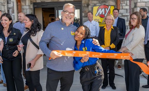 Professionals of My Place hotels are pictured holding the ribbon for the grand opening.