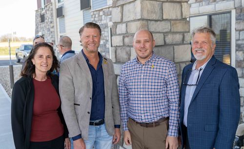 Four professionals are pictured smiling standing in front of the new hotel.