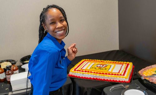 The general manager of the new hotel is pictured smiling in front of a cake with the My Place logo.