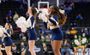 Two cheerleaders wearing navy blue and white lead a cheer to an off-camera crowd.