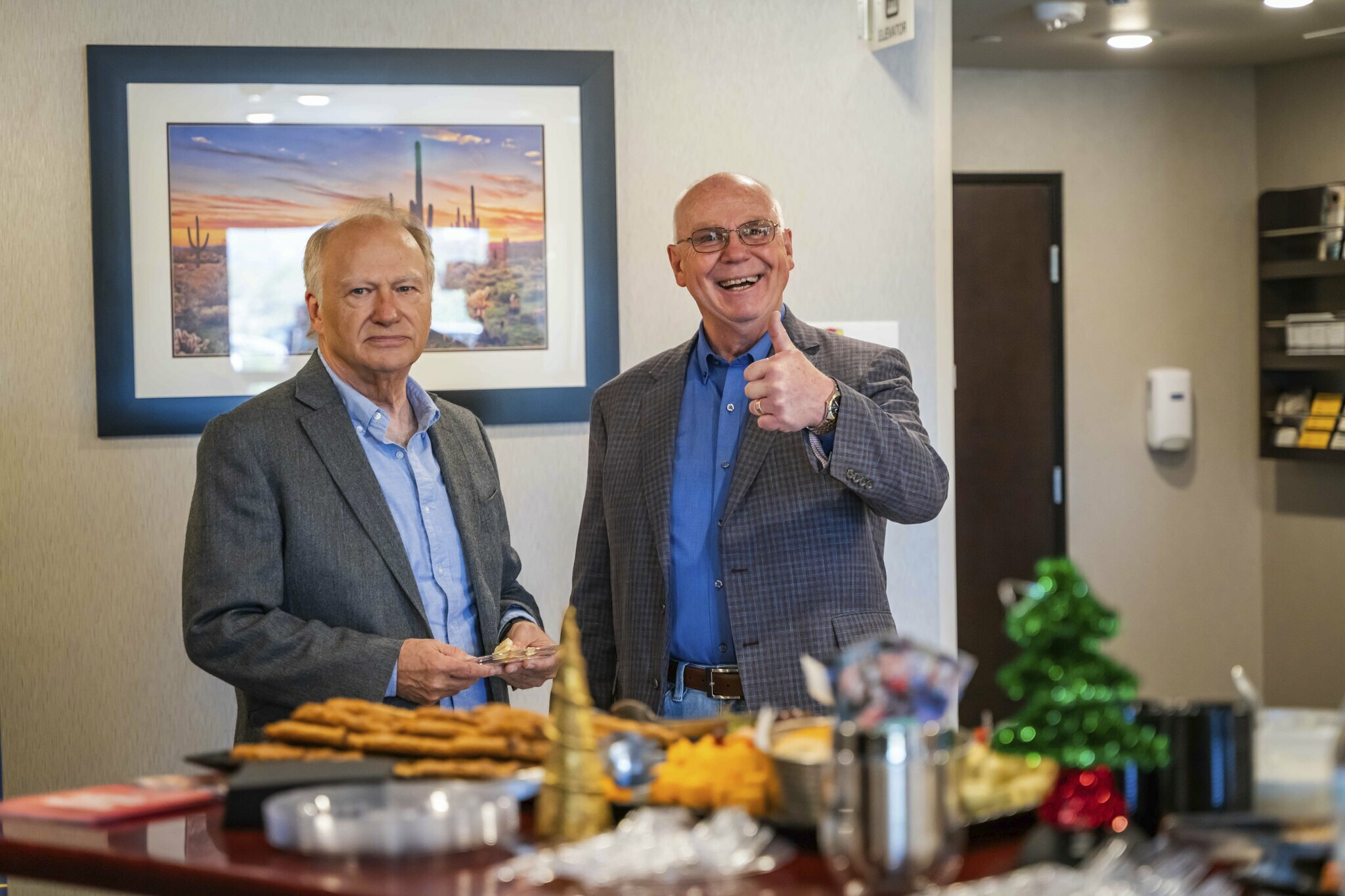 Two men smile while one gives a thumbs up as they talk near the snacks during the grand opening ceremony at the new hotel in Nampa, Idaho.