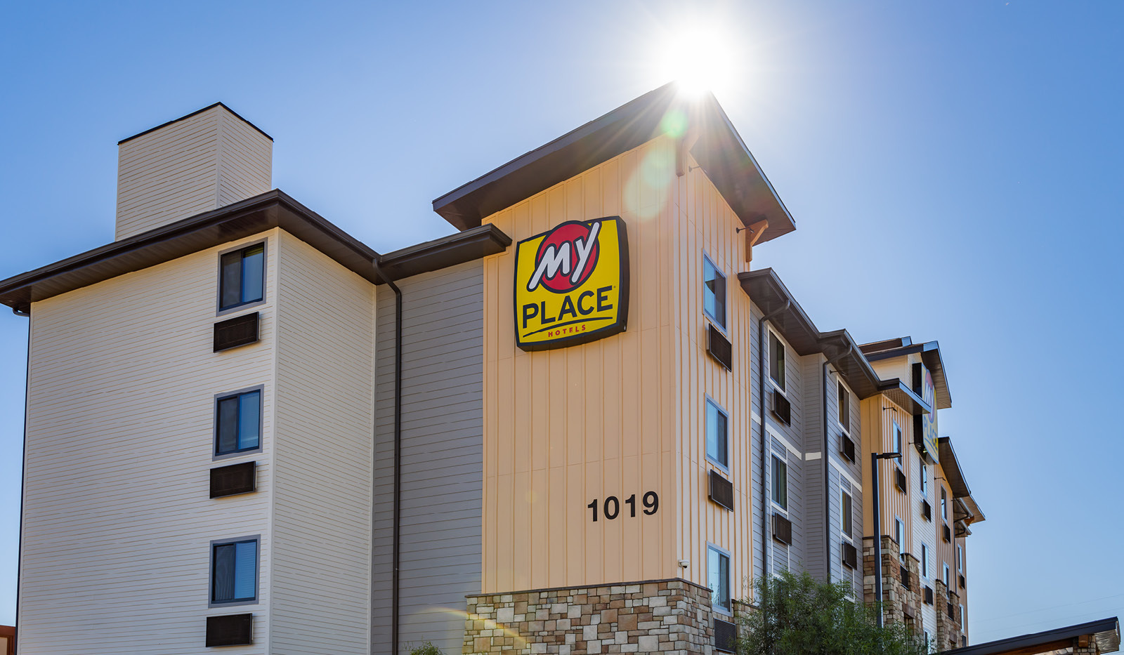 Side view of hotel with sun peaking around top of building.