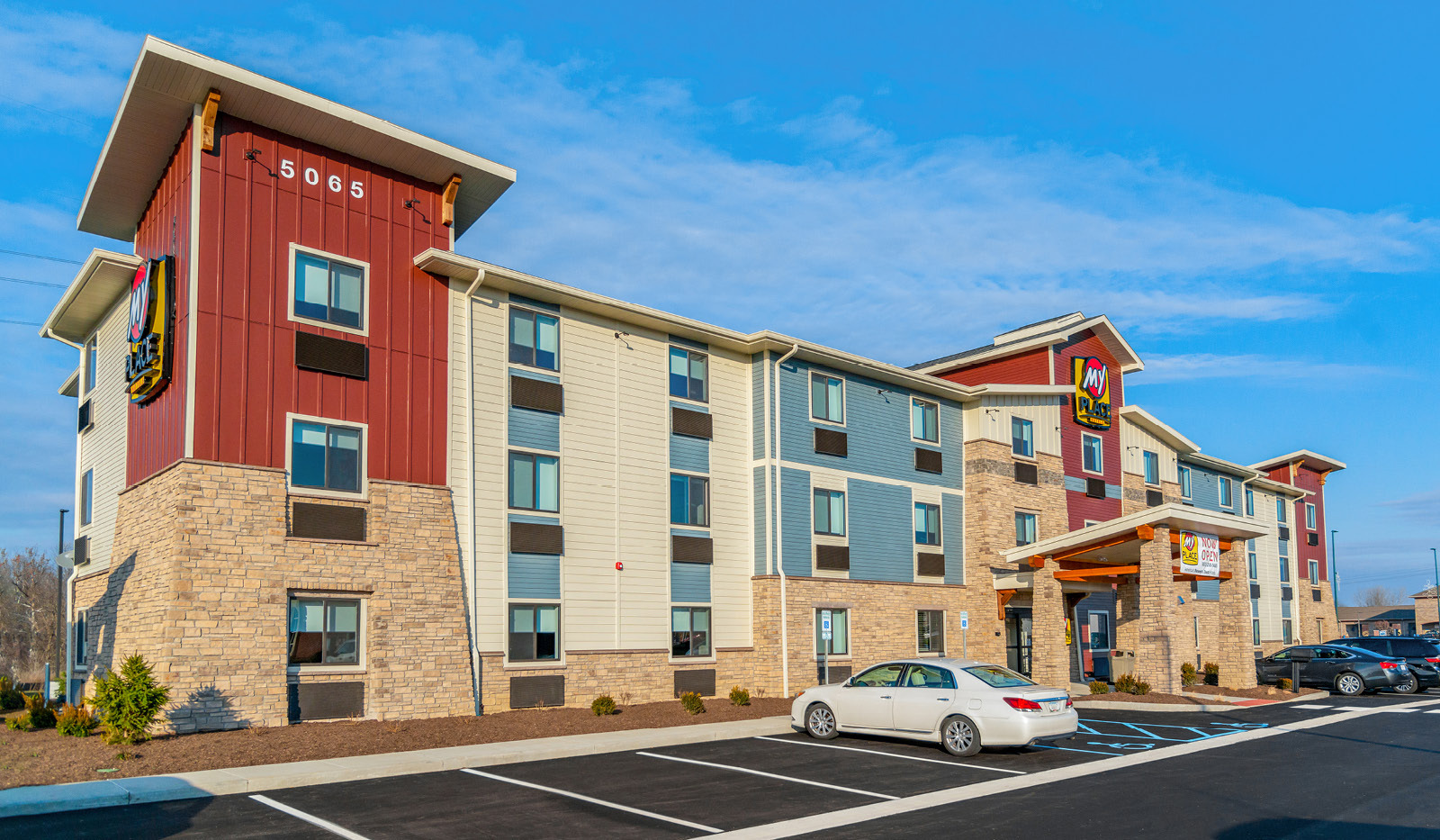 Exterior of My Place Hotel-Plainfield, IN under a blue, cloudy sky.
